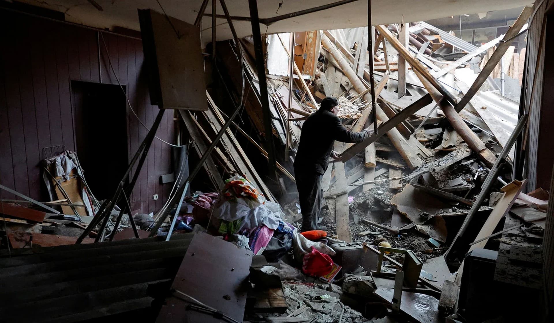 Local resident stands amid debris while gathering his belongings in an apartment inside a building heavily damaged in recent shelling in Horlivka