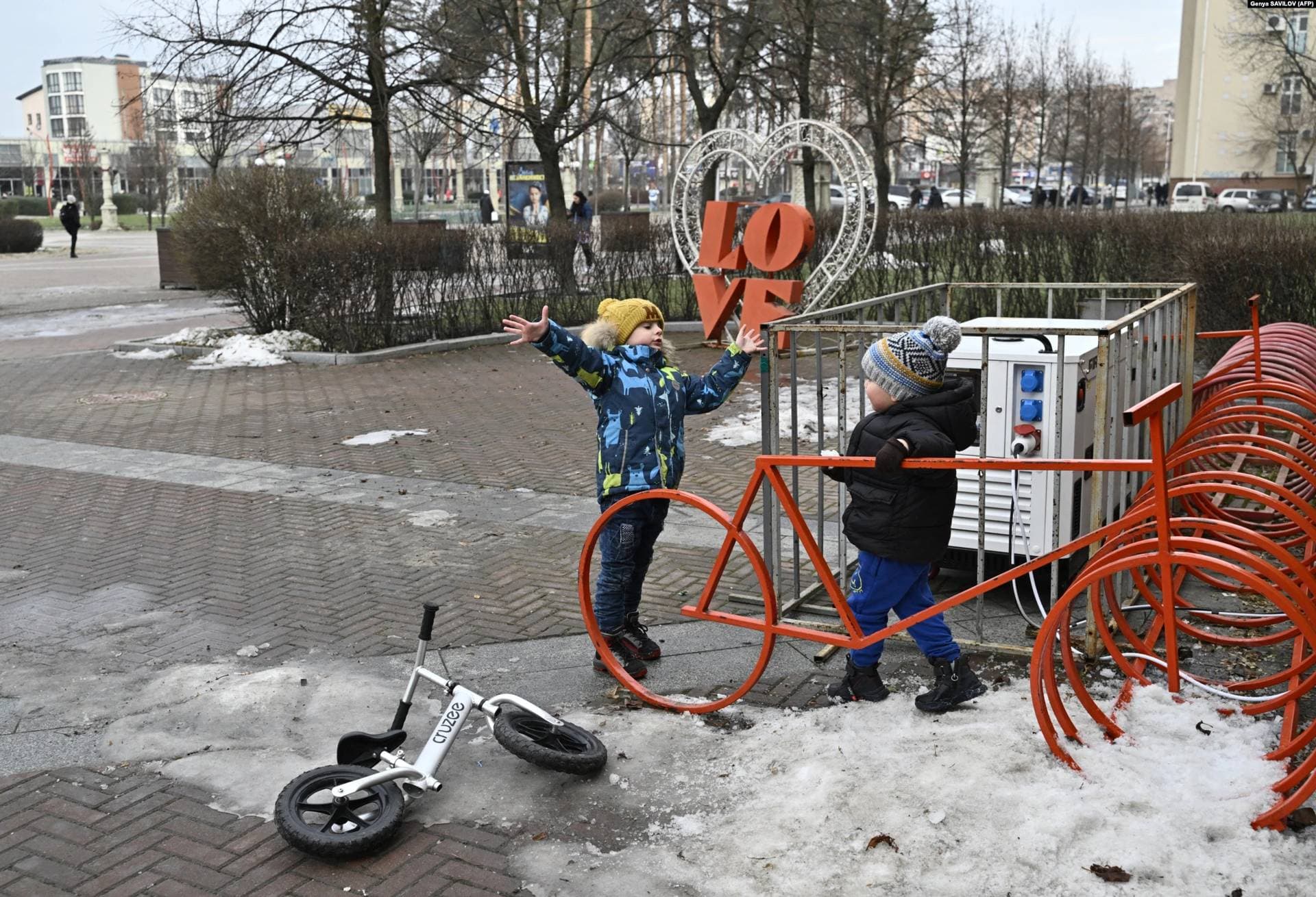 Children play near a generator in front of the library