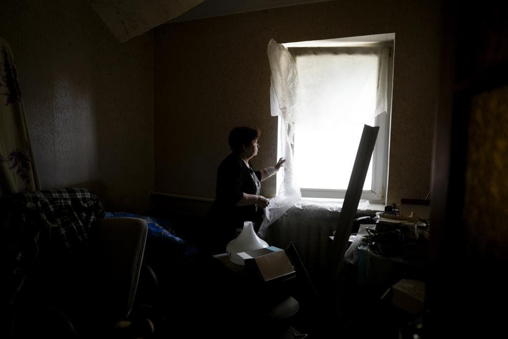 Nataliia Fedorova shows lack of glass at a window of her home ruined by attacks in Irpin