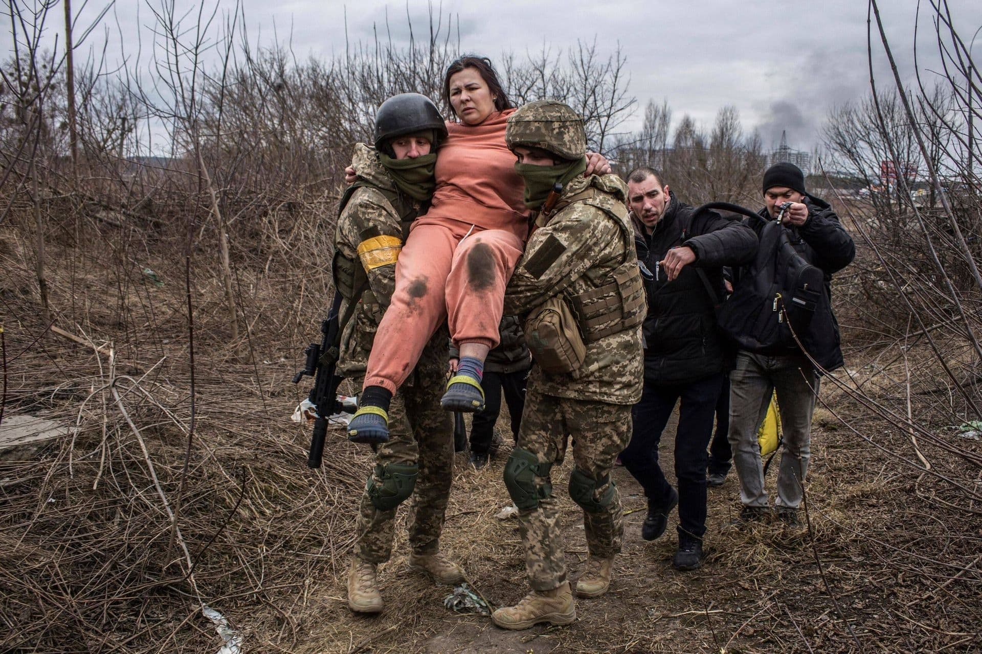 A woman is carried by Ukrainian soldiers while fleeing the town of Irpin