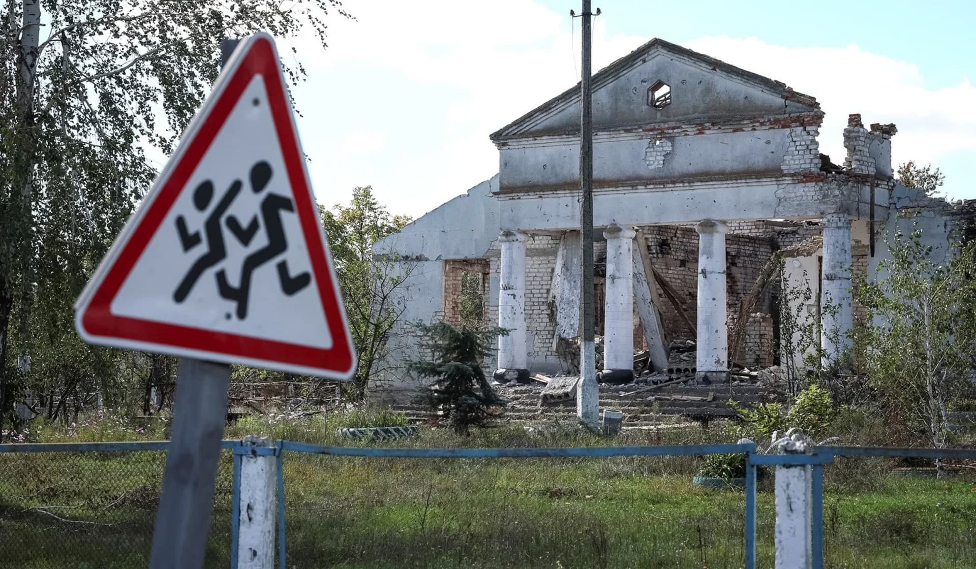 A road sign and a destroyed building in the village of Zalyman
