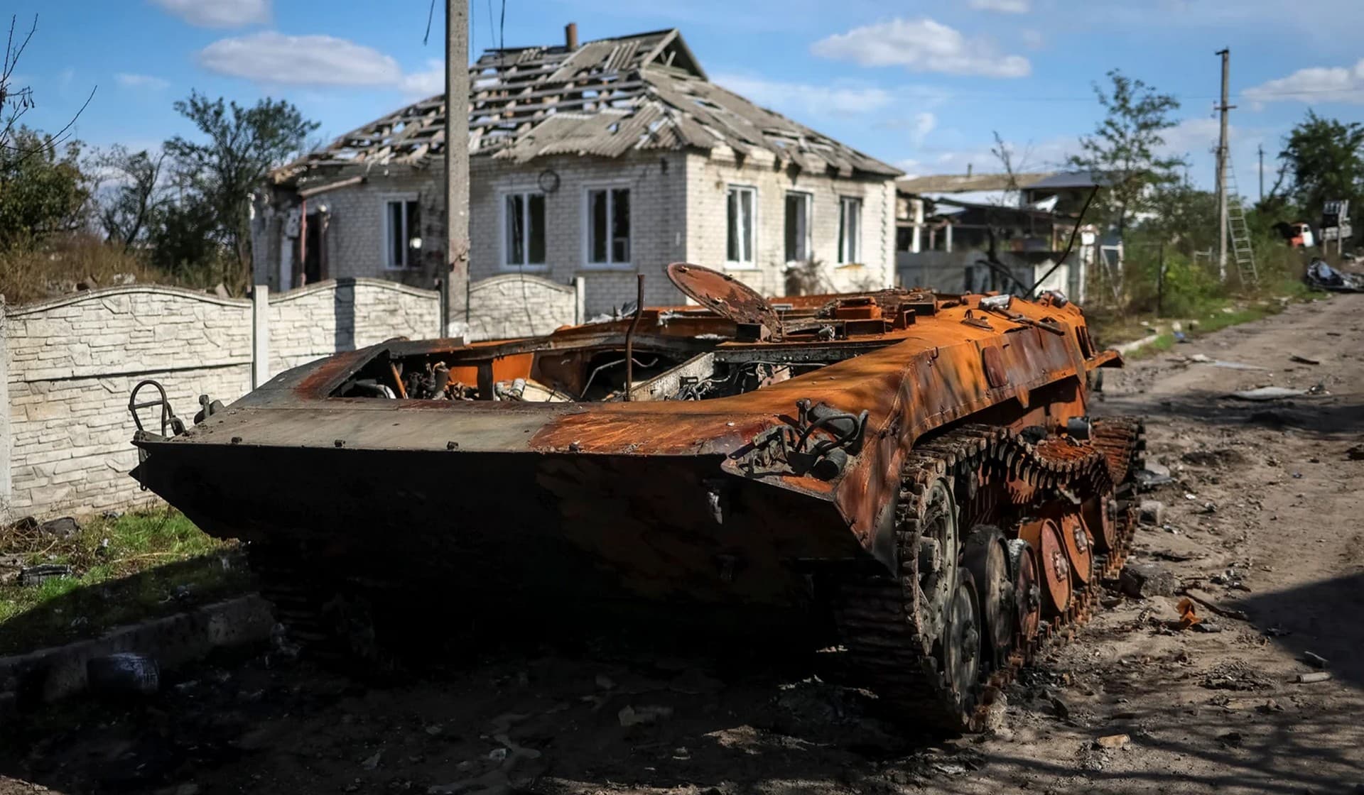 A destroyed Russian tank near a destroyed building in the village of Kamyanka