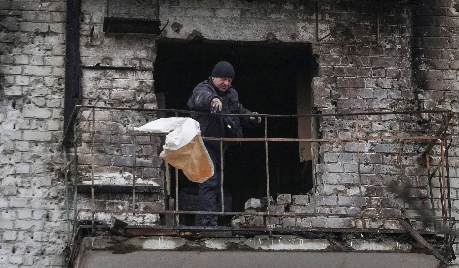 A resident throws garbage from the balcony of his apartment damaged during Russian missile strikes in the town of Balakliia