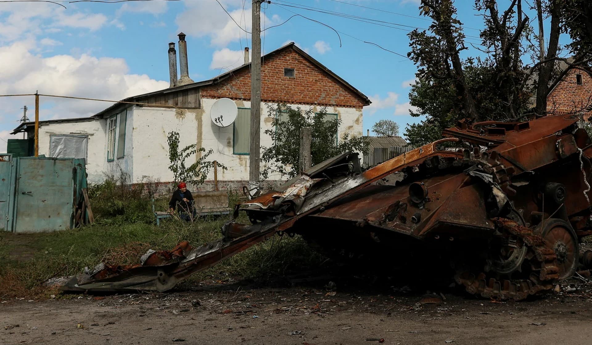 A woman looks at a destroyed Russian armored fighting vehicle in the town of Balakliia