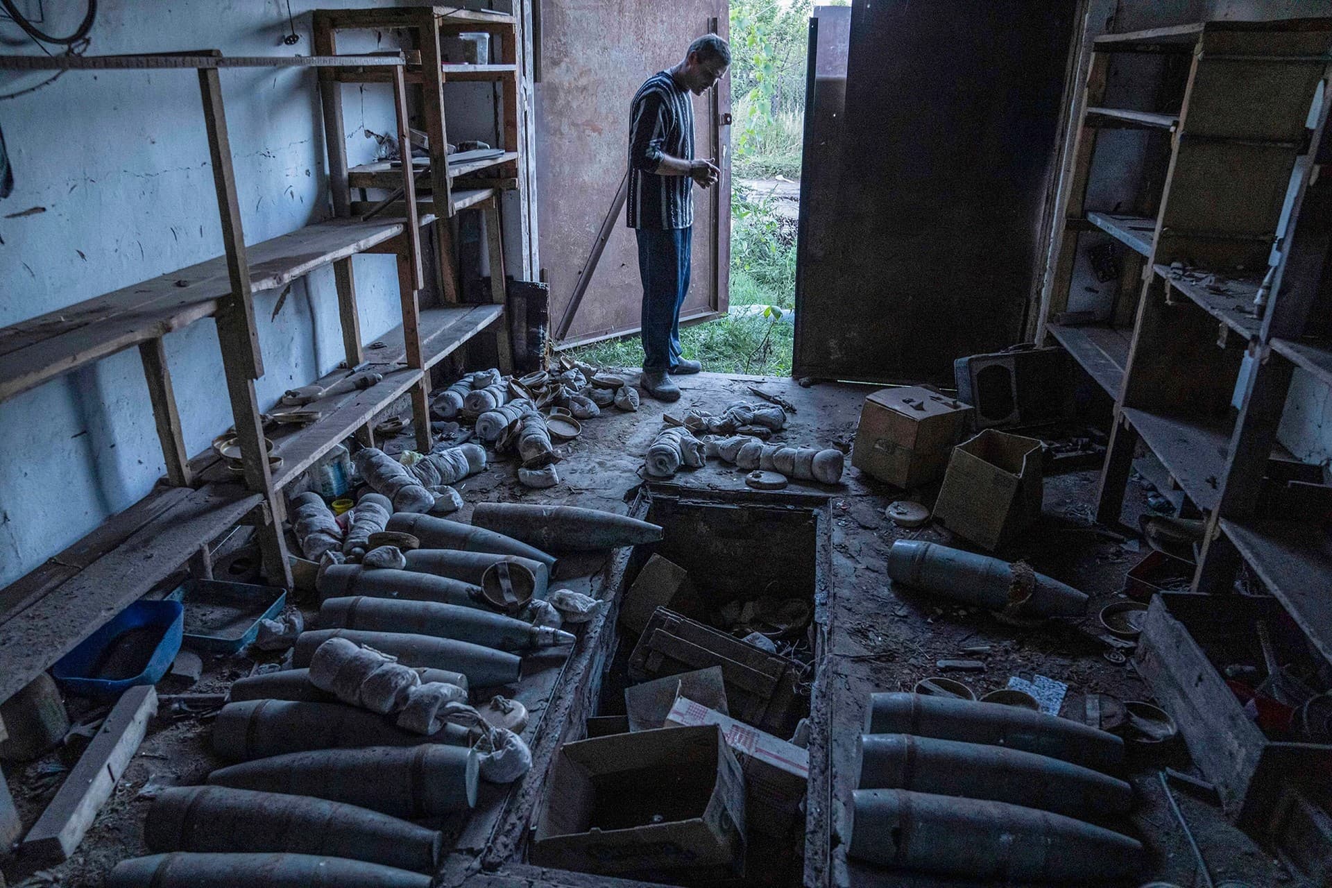 A man stands in the garage with Russian artillery shells in the recently retaken area of Kamyanka