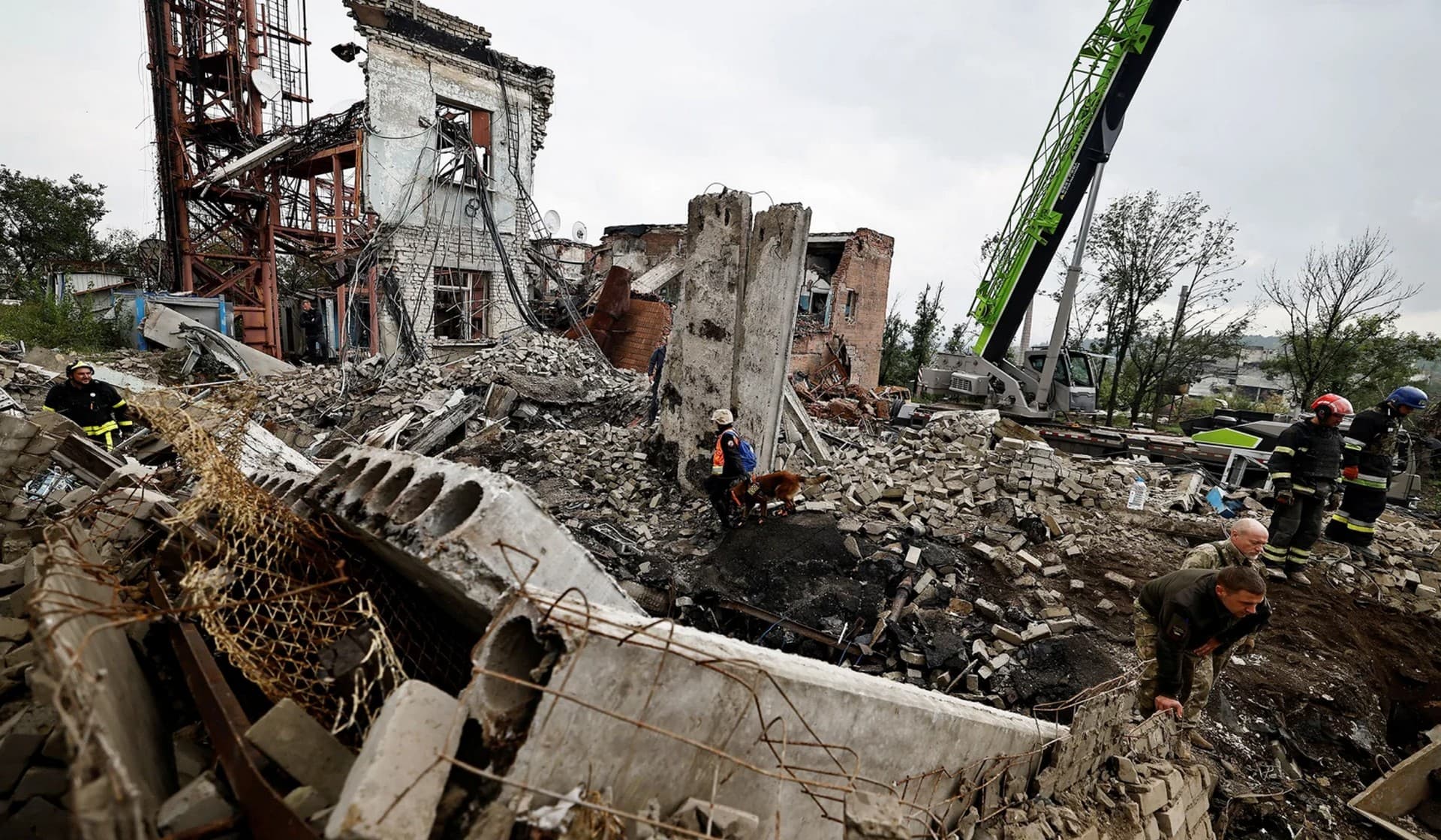 Firefighters and Ukrainian army soldiers search for bodies of people killed during a Russian attack among the remains of a building beside a TV tower in the recently liberated town of Izium