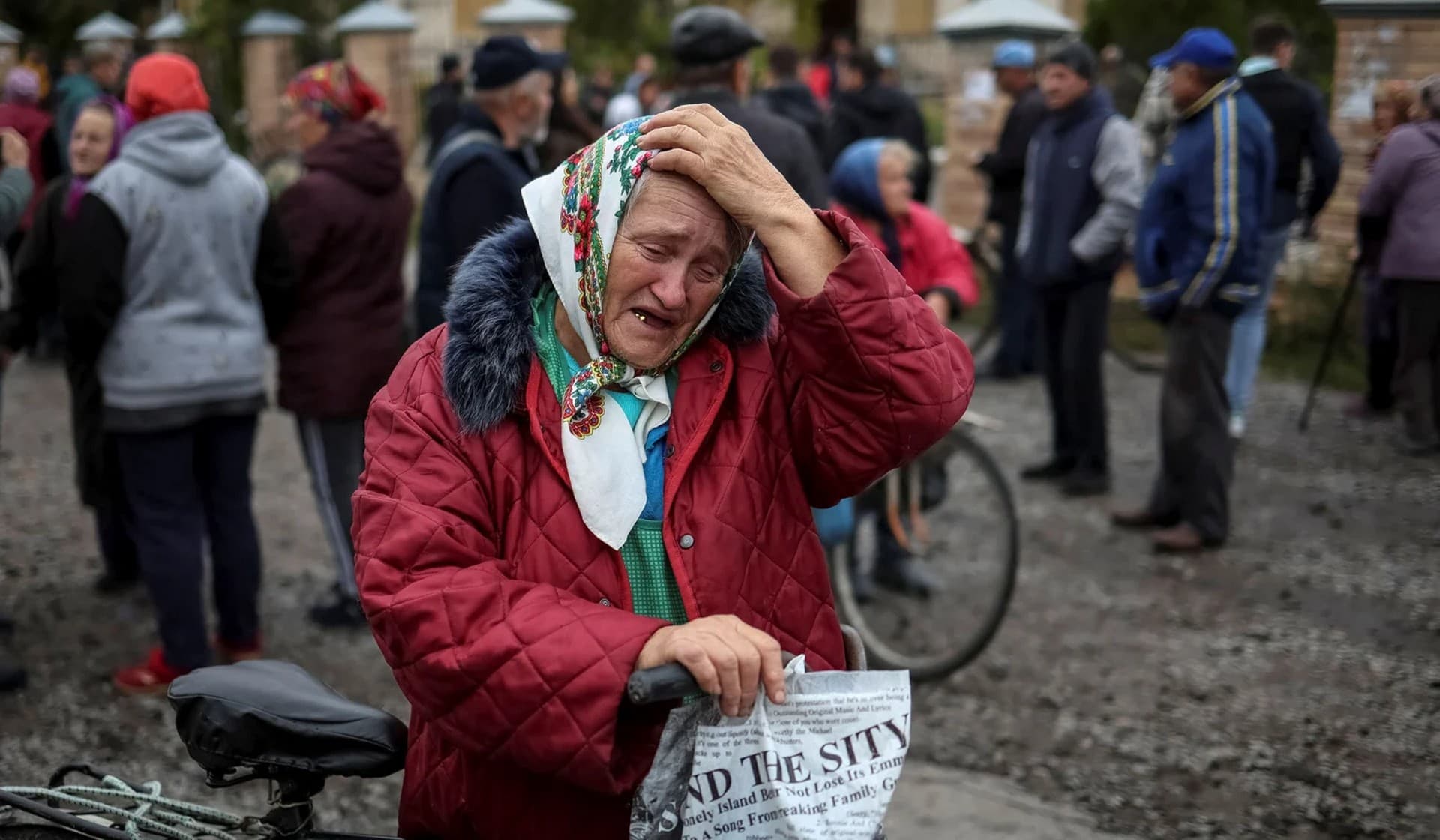 A local resident reacts as she waits for a car distributing humanitarian aid in the village of Verbivka