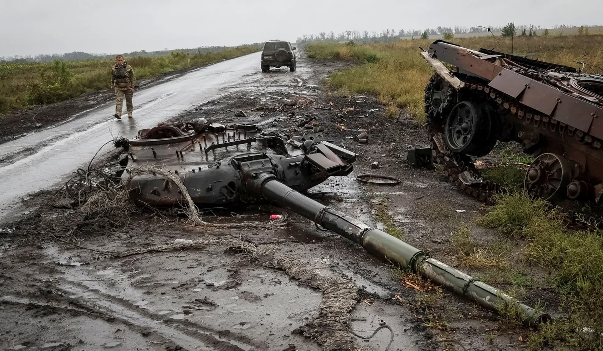 A Ukrainian serviceman passes by a destroyed Russian tank near the village of Dolyna