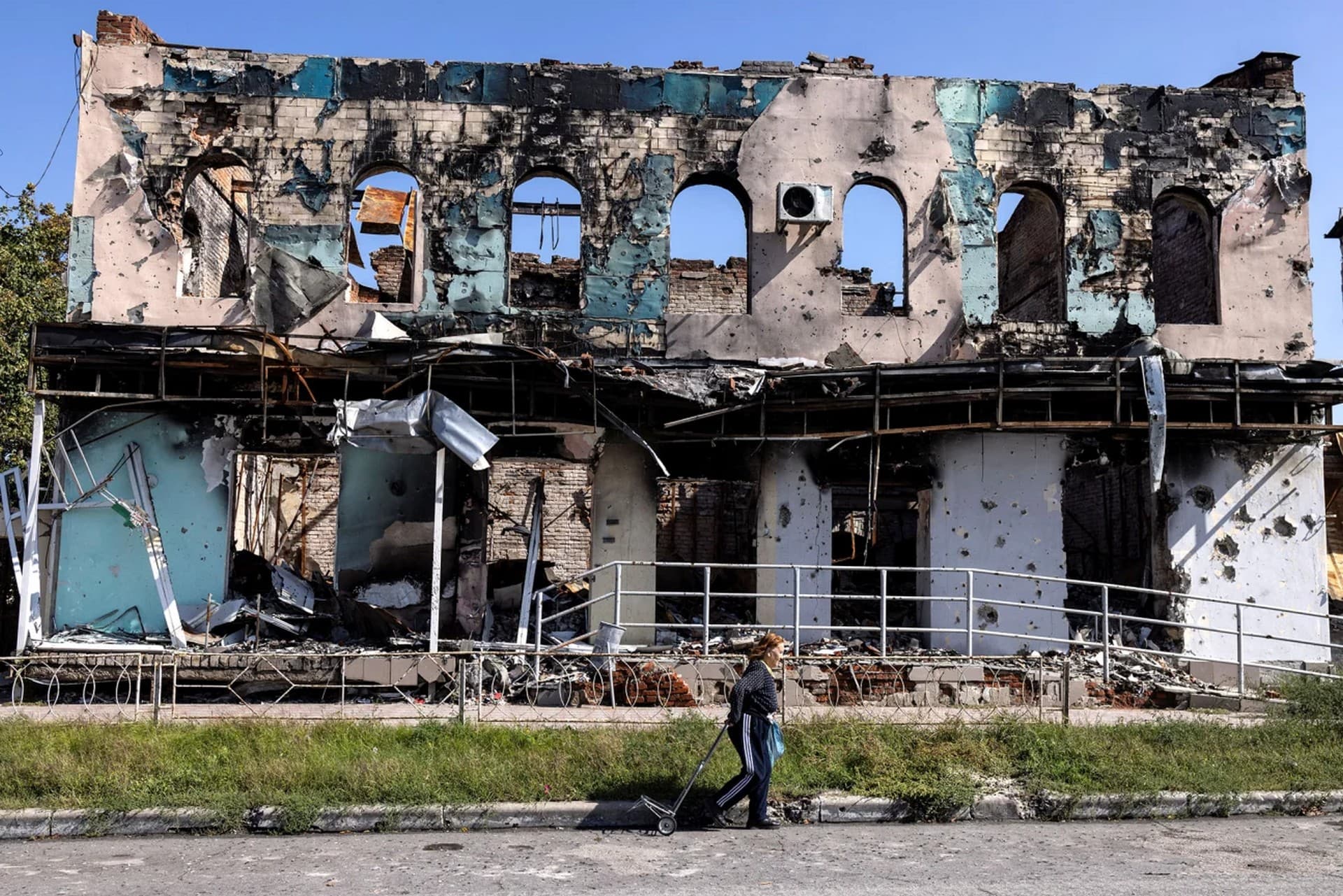 A woman walks past a destroyed building, as Russia's attack on Ukraine continues, in the town of Izium