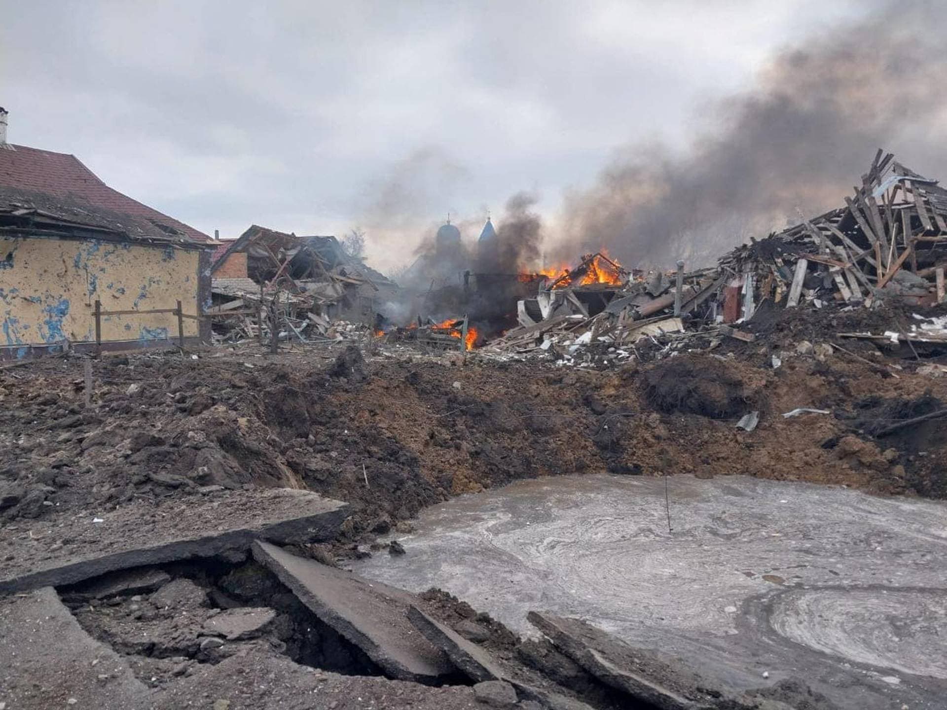 A view shows a bomb crater and residential buildings destroyed by a Russian air strike in the village of Borova