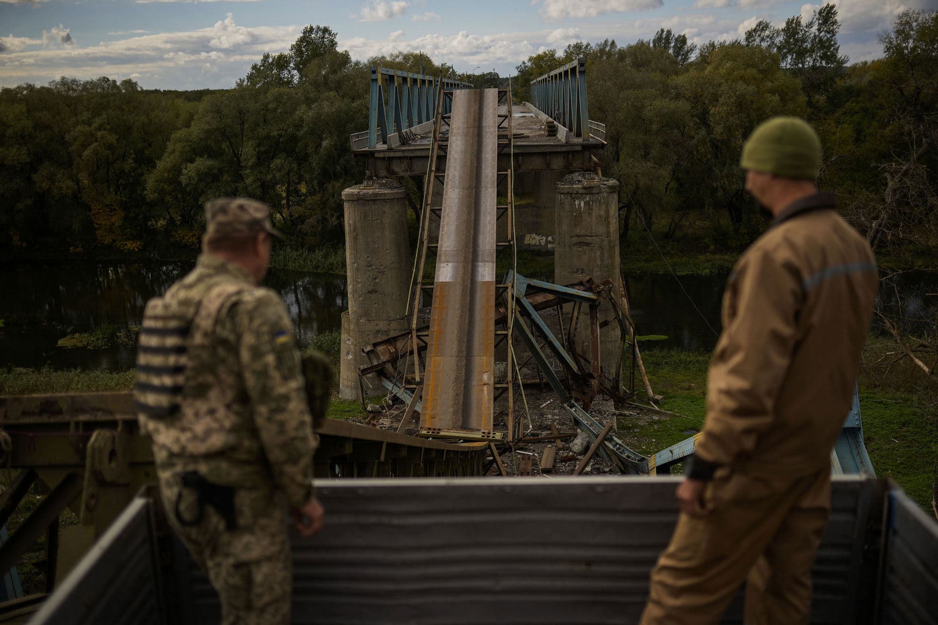Ukrainian soldiers remove metal structure pieces as they work on a bridge damaged during fighting with Russian troops in Izium