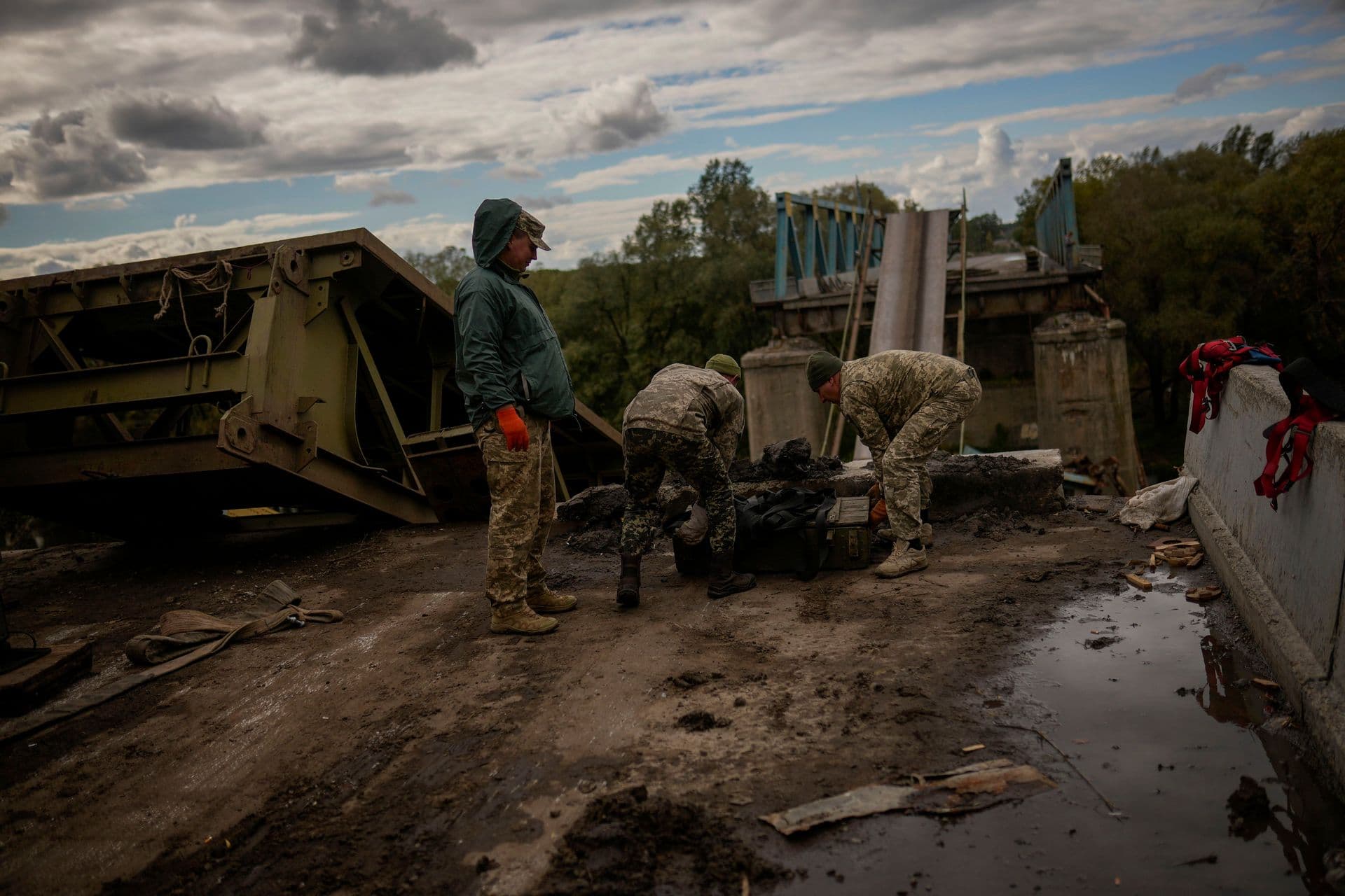 Ukrainian soldiers remove metal pieces as they work on a bridge damaged during fighting with Russian troops in Izium