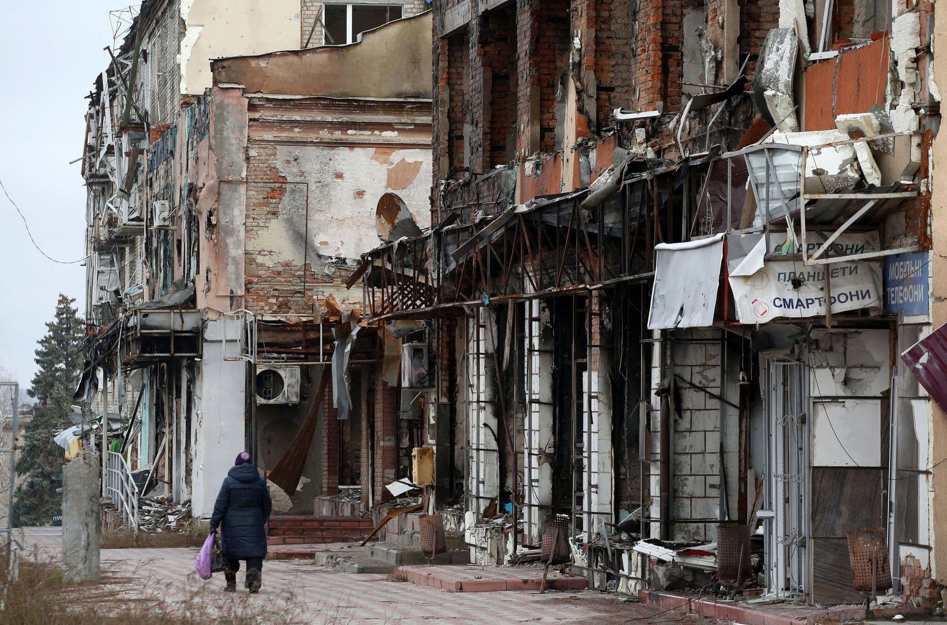 A resident walks past heavily damaged buildings in the Ukrainian town of Izyum, Kharkiv region, on November 25.