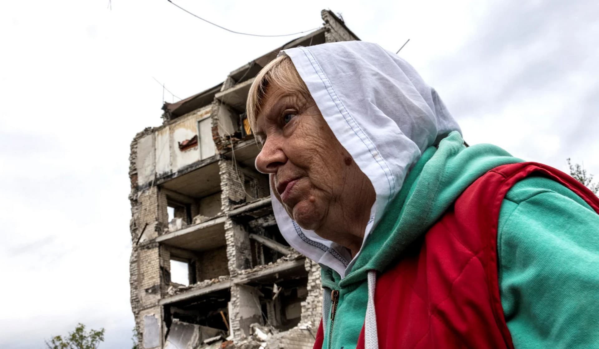A woman stands in front of a destroyed building in the town of Izium