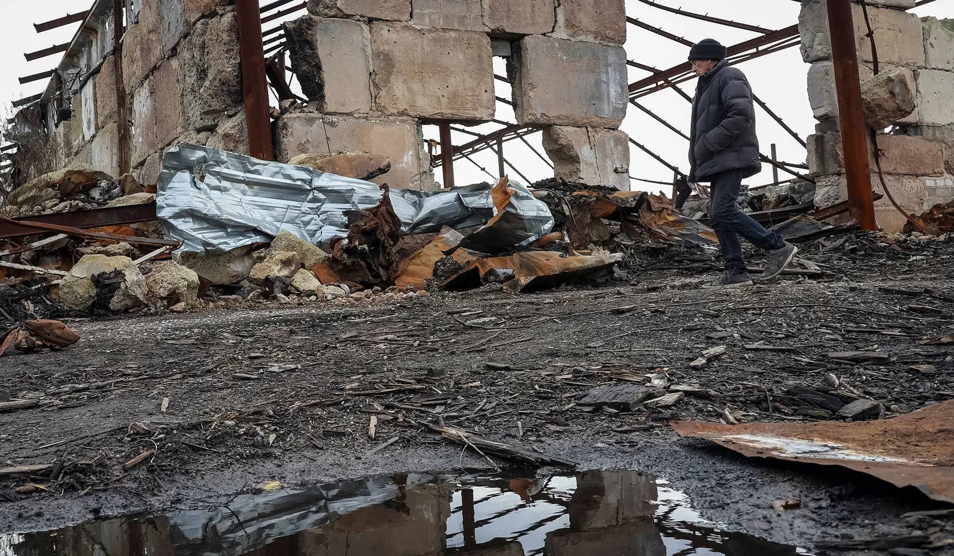 A local resident walks amidst the debris at a site of a farm that was destroyed last year by Russian military strike in the village of Kamianka