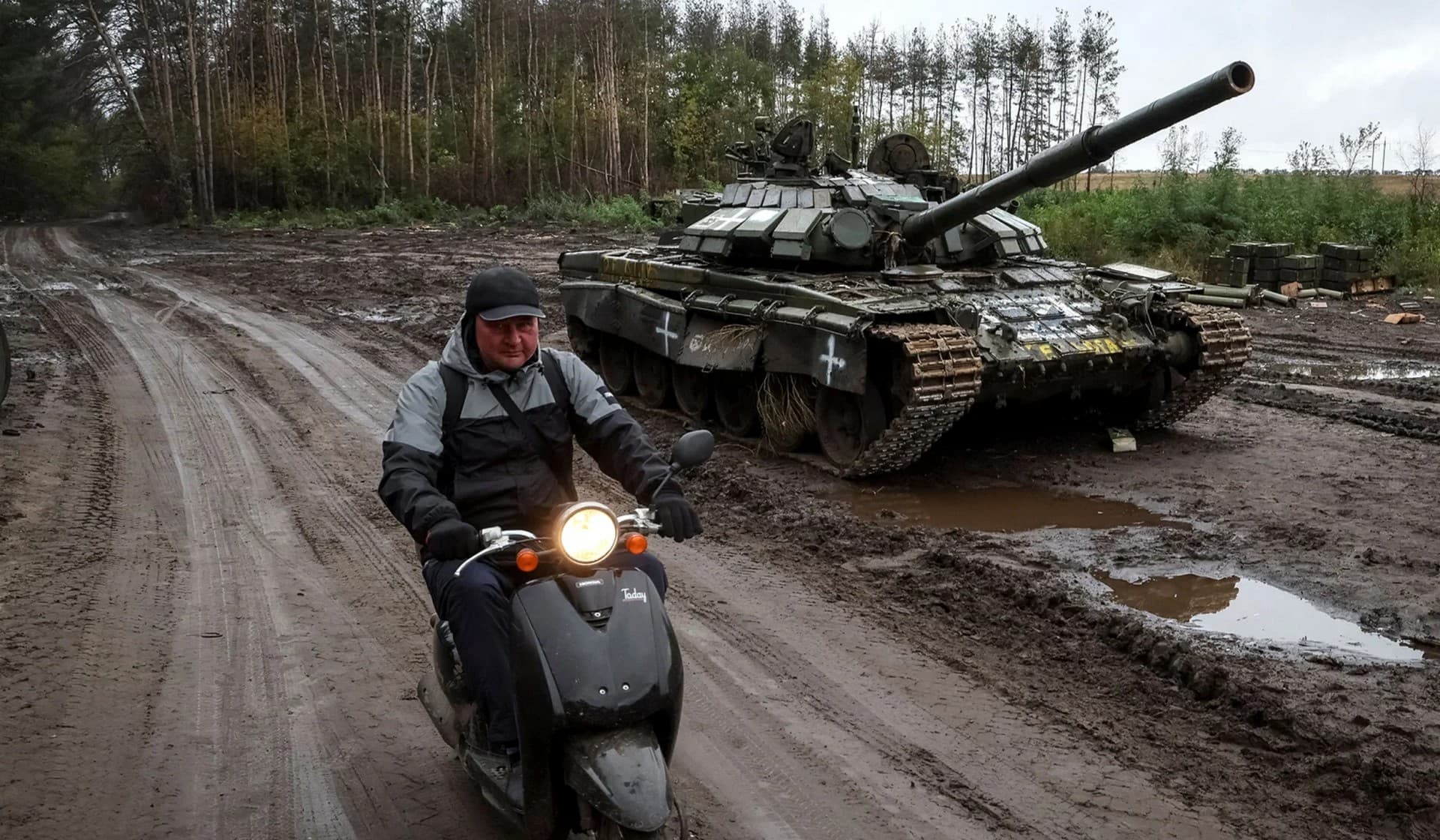 A local resident rides a scooter near a destroyed Russian tank in the town of Izium