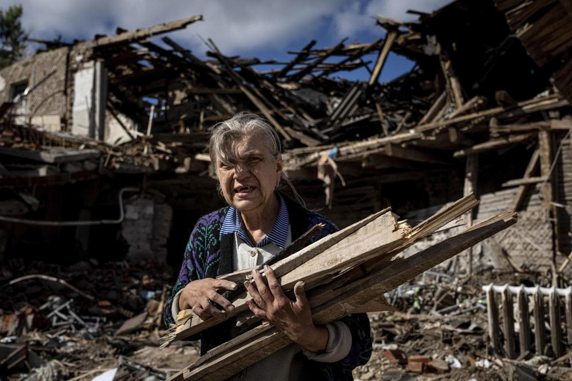 A woman collects wood for heating from a destroyed school where Russian forces were based in the recently retaken area of Izium