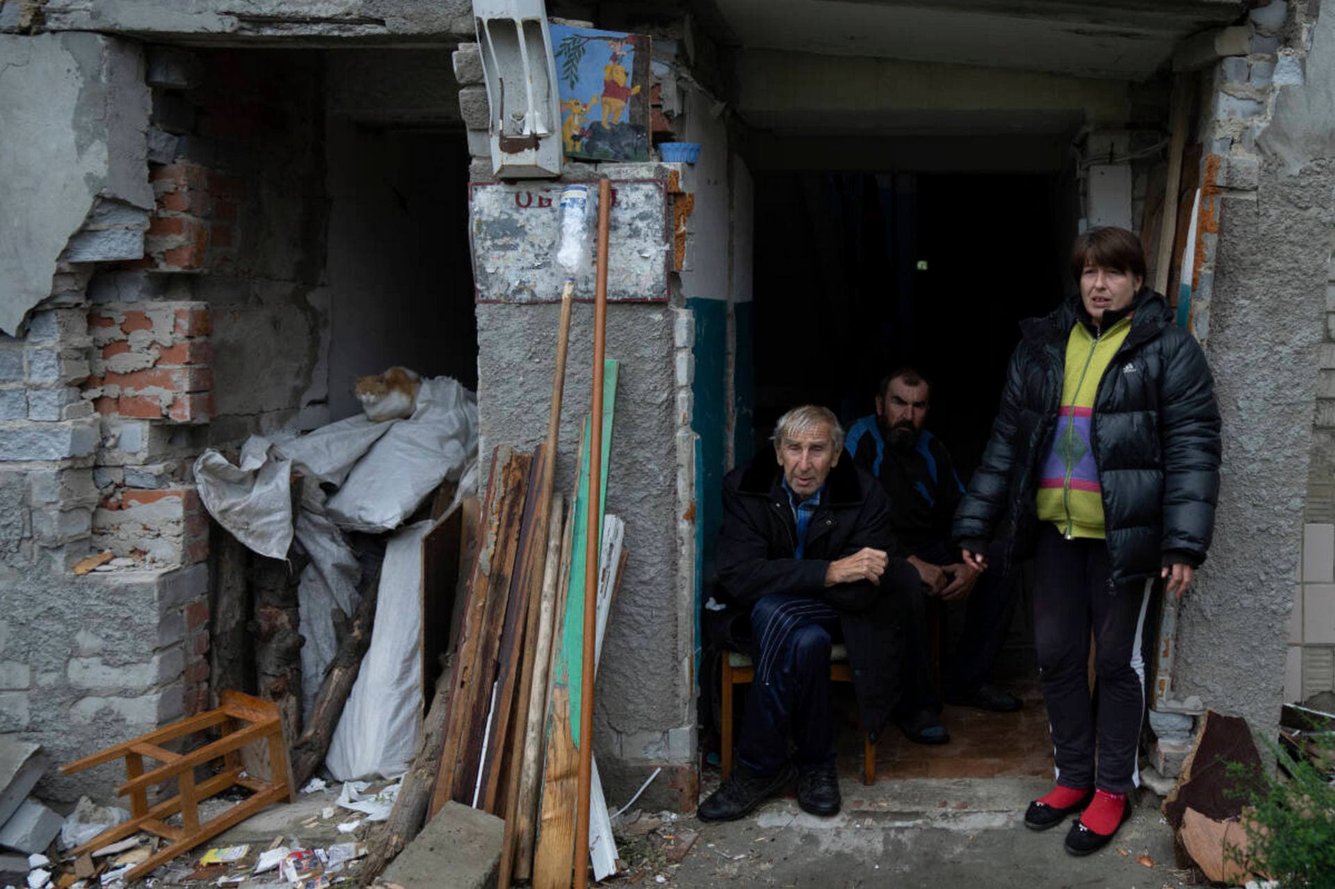 Svetlana Iezyk, right, Volodymyr Iezyk, left, and Andrii Iezyk gather at the entrance of their apartment in the recently retaken area of Izium