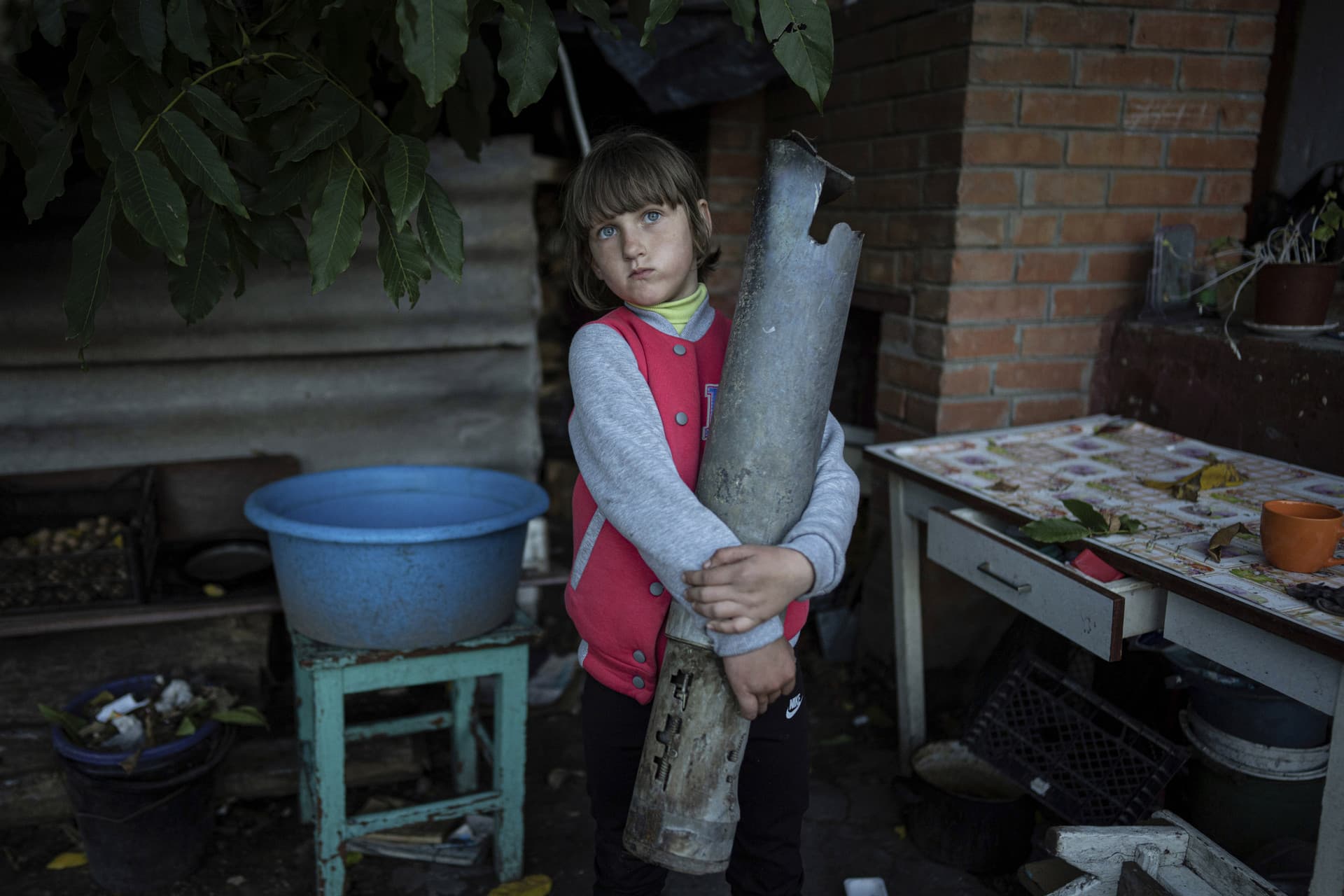 Veronika Tkachenko holds a piece of a Grad rocket which hit her family's house in the recently retaken town of Izium