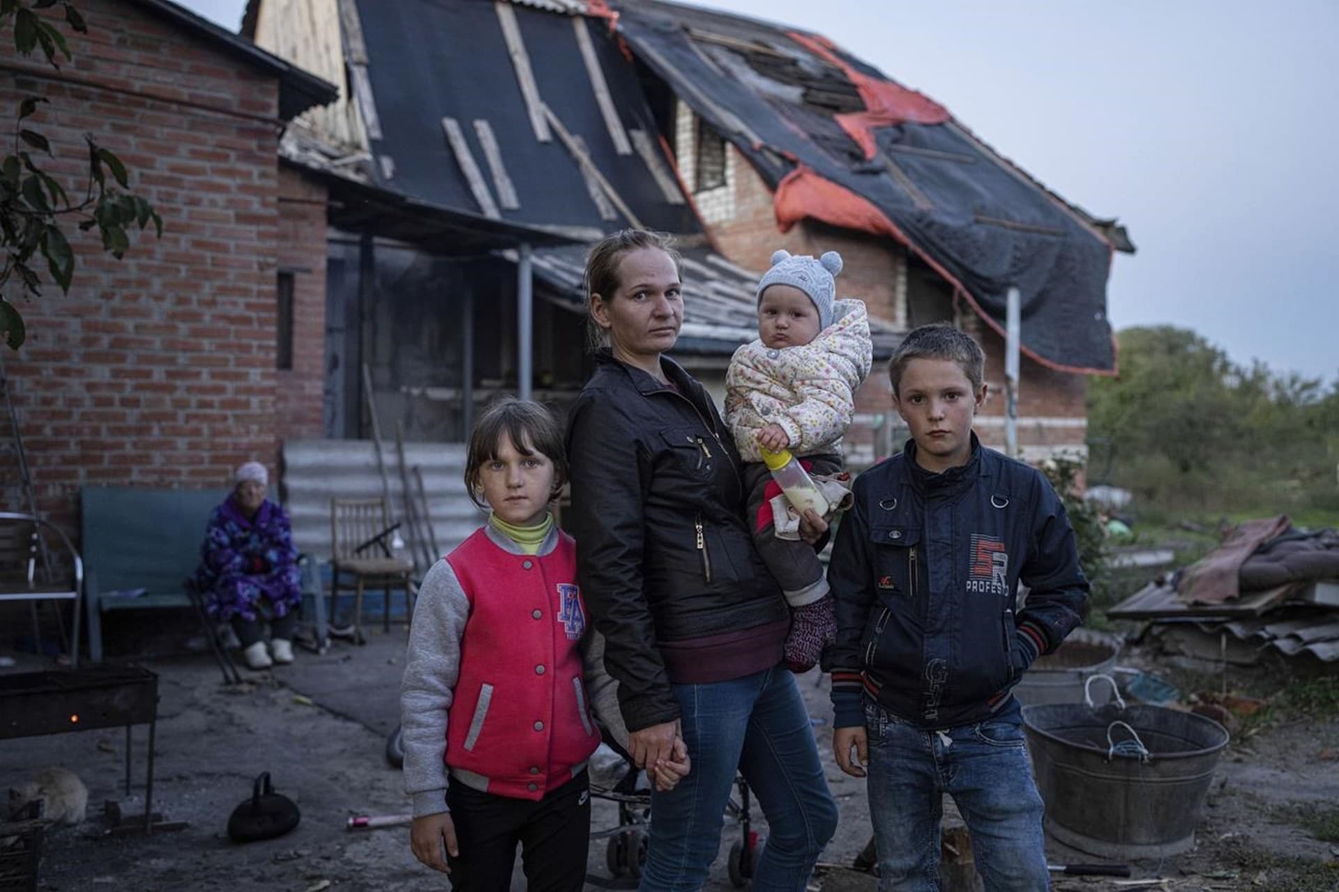 Margaryta Tkachenko with her children pose for photo in front of their damaged house in the recently retaken town of Izium