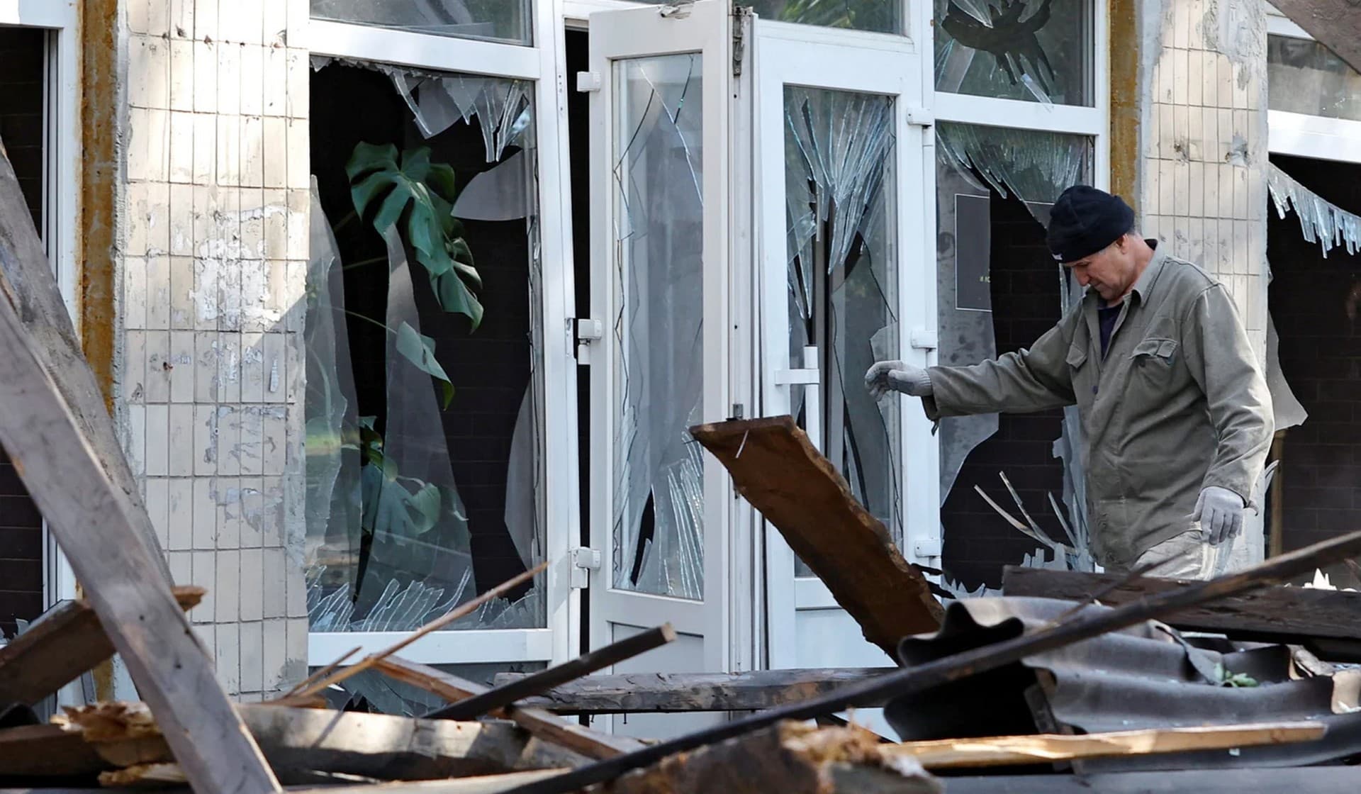 A man removes debris of a building destroyed by recent shelling in the city of Kadiivka