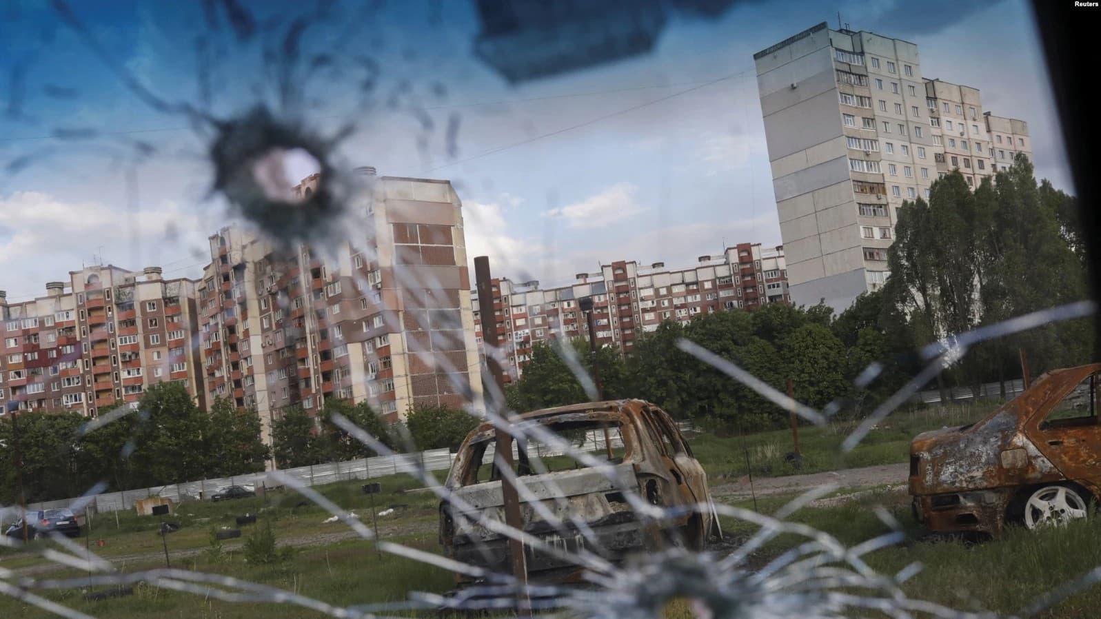 Burned cars are pictured through the glass of a damaged car in Kharkiv