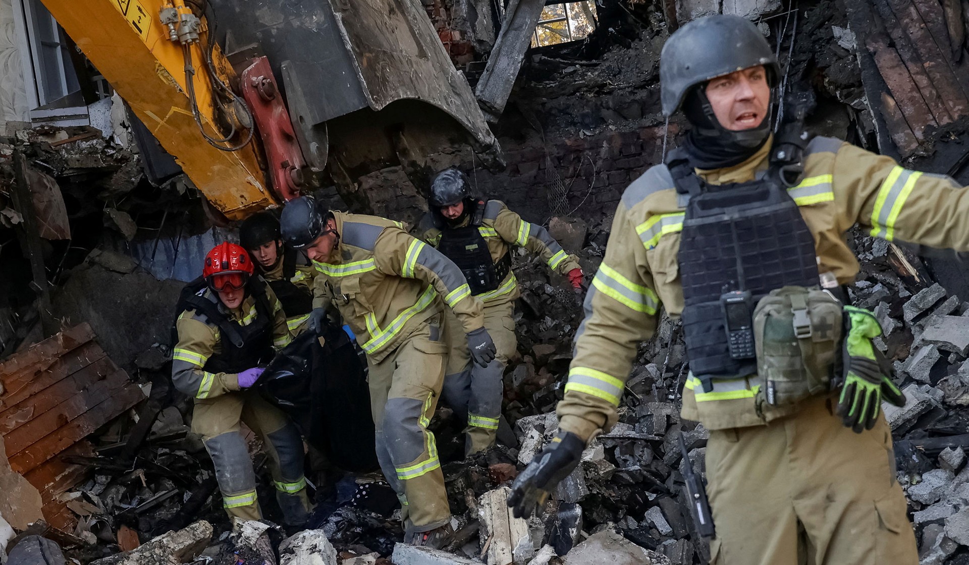 Rescuers carry the body of a killed person found under debris of an apartment building damaged during a Russian jet drone strike in Kharkiv