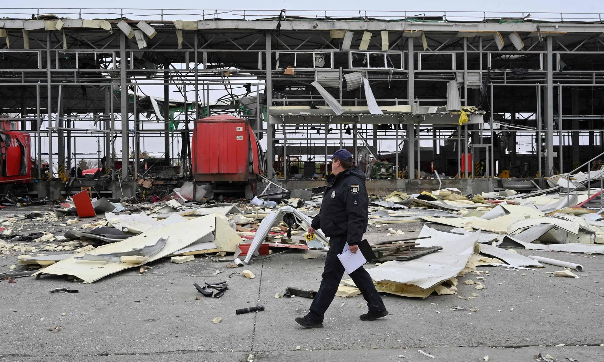 A Ukrainian police officer walks past a damaged mail depot after a missile strike in Korotych