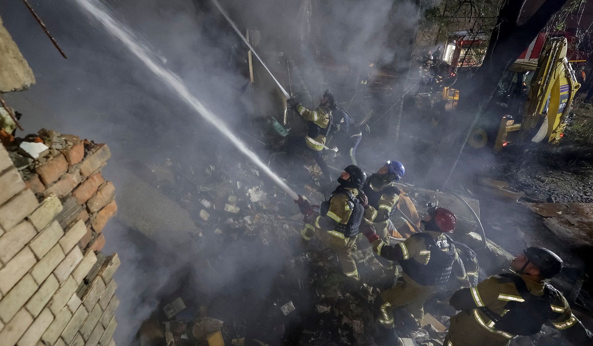 Firefighters work at a site of an apartment building damaged during a Russian jet drone strike in Kharkiv