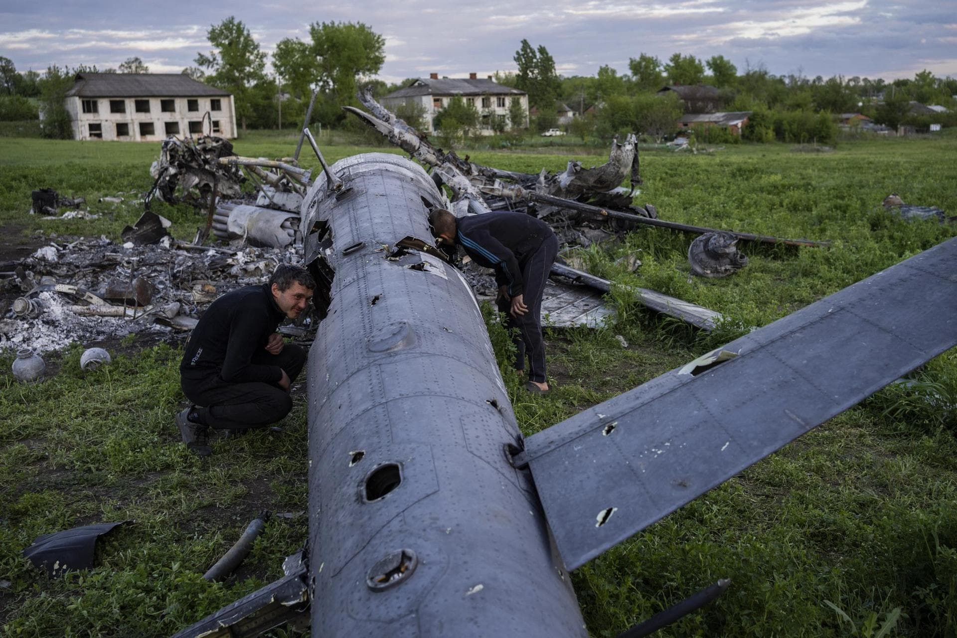 Oleksiy Polyakov, right, and Roman Voitko check the remains of a destroyed Russian helicopter that lies in a field in the village of Malaya Rohan, Kharkiv region