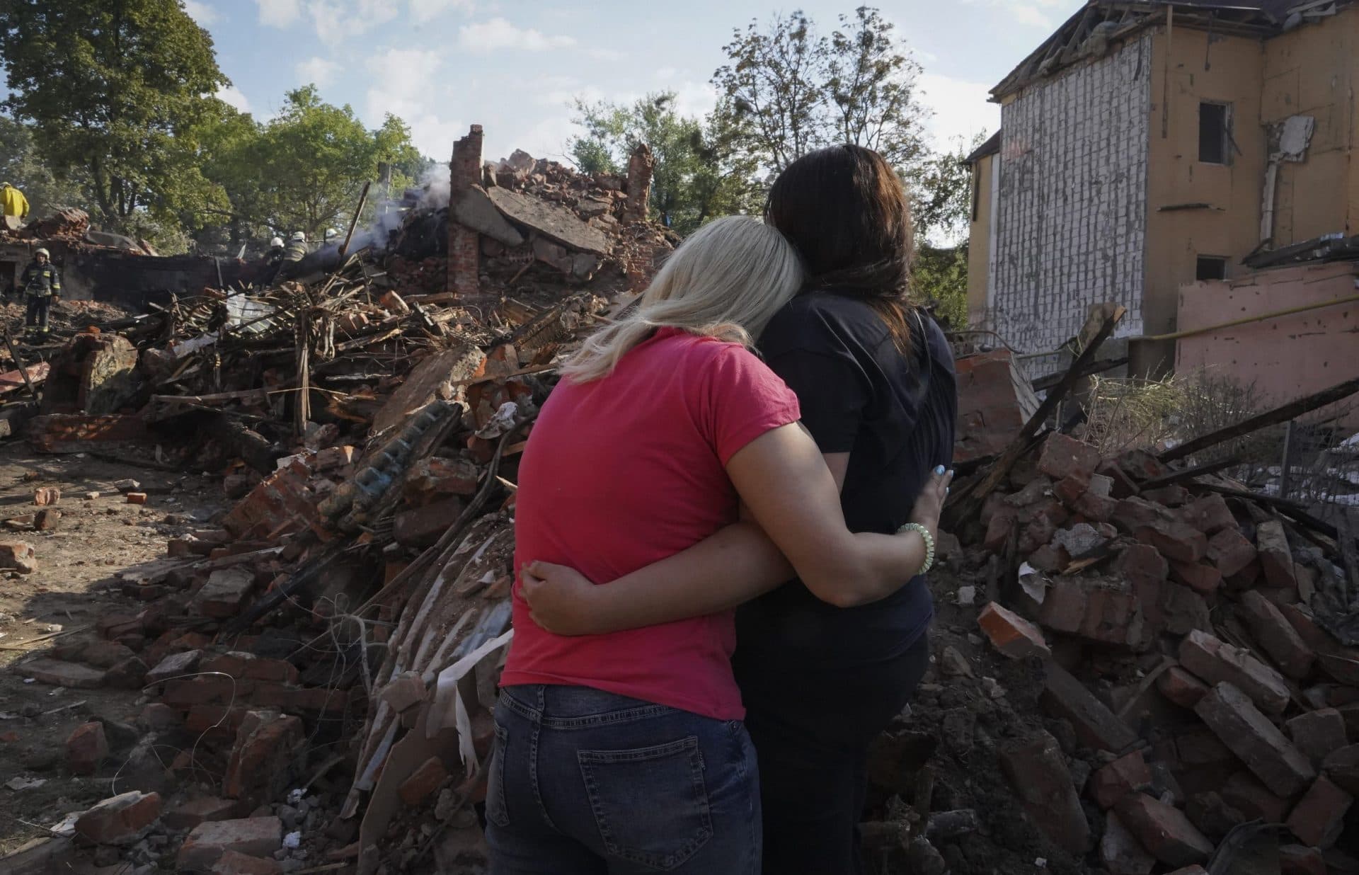 Ukrainian women hug in front of a building destroyed during a missile strike in Kharkiv