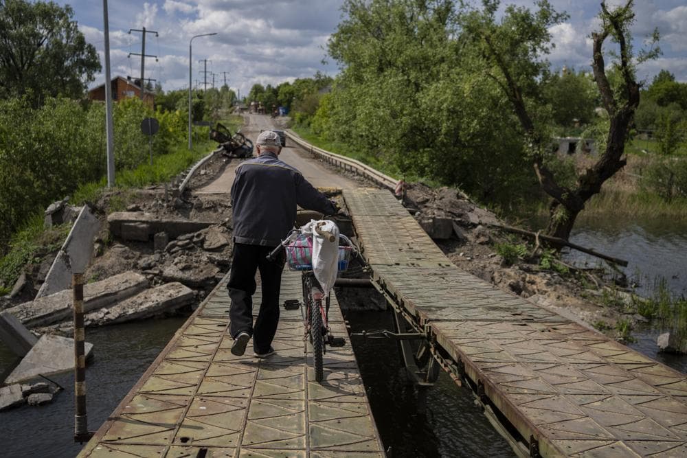 A man pushes his bicycle across a repaired bridge in Vilkhivka, outside Kharkiv