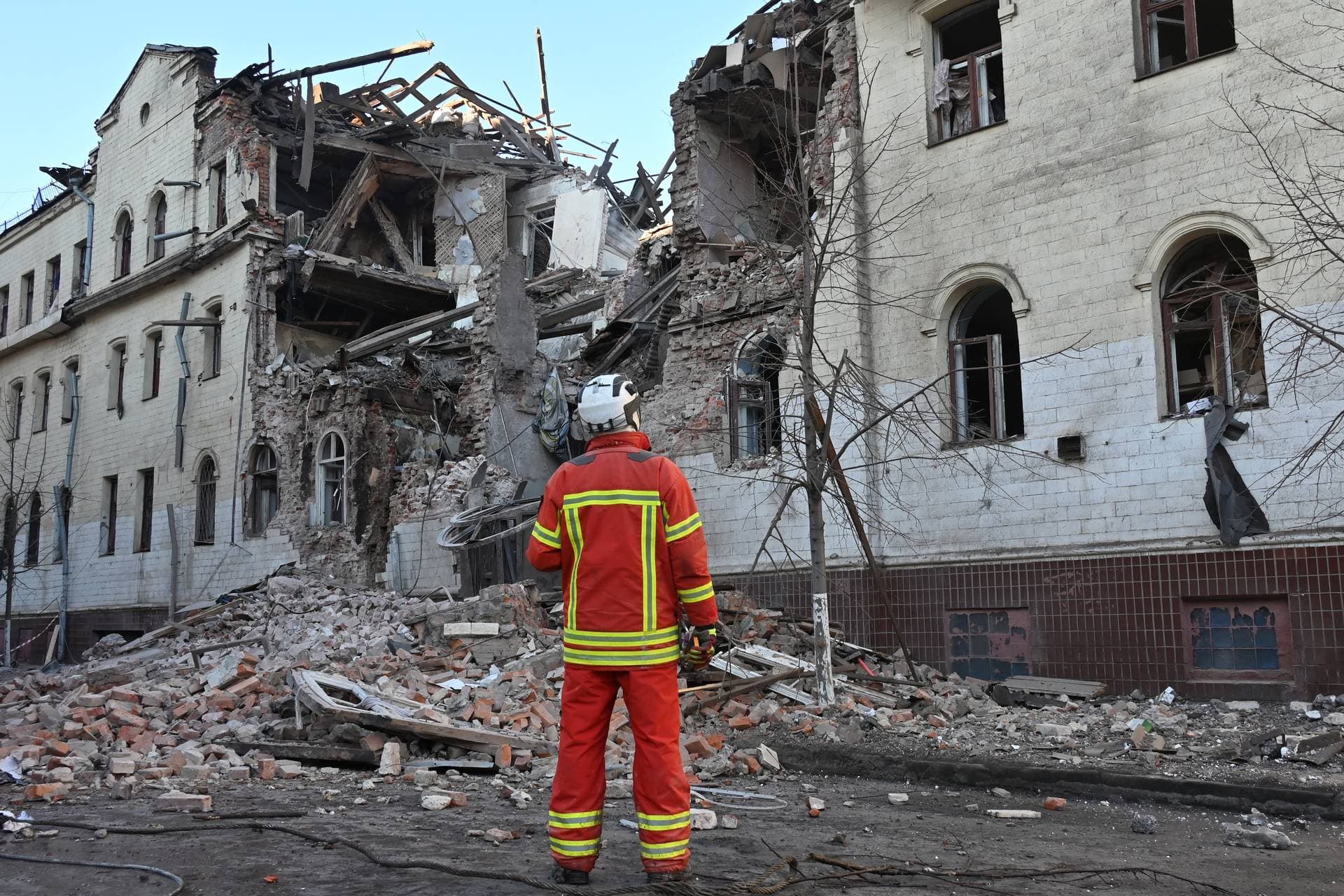 A rescue worker stands next to a residential building partially destroyed as a result of a missile attack in Kharkiv