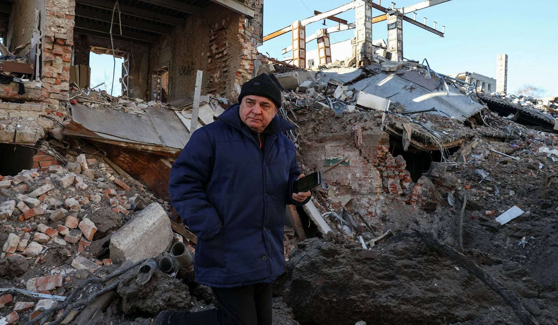 A local resident stands next to a building destroyed by a Russian missile strike in Kharkiv