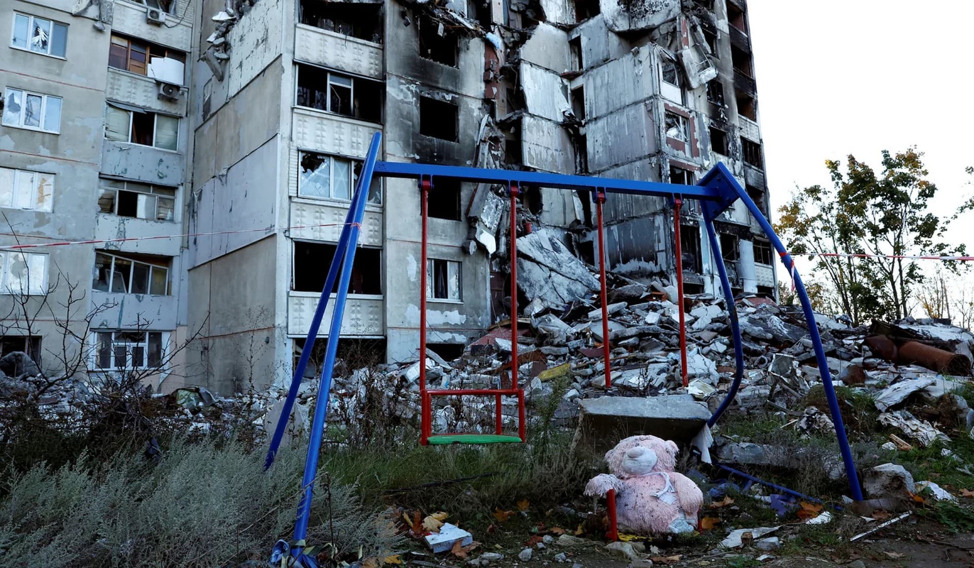 A pink teddy bear lies on the ground in front of residential apartments destroyed by Russian military strikes in Kharkiv