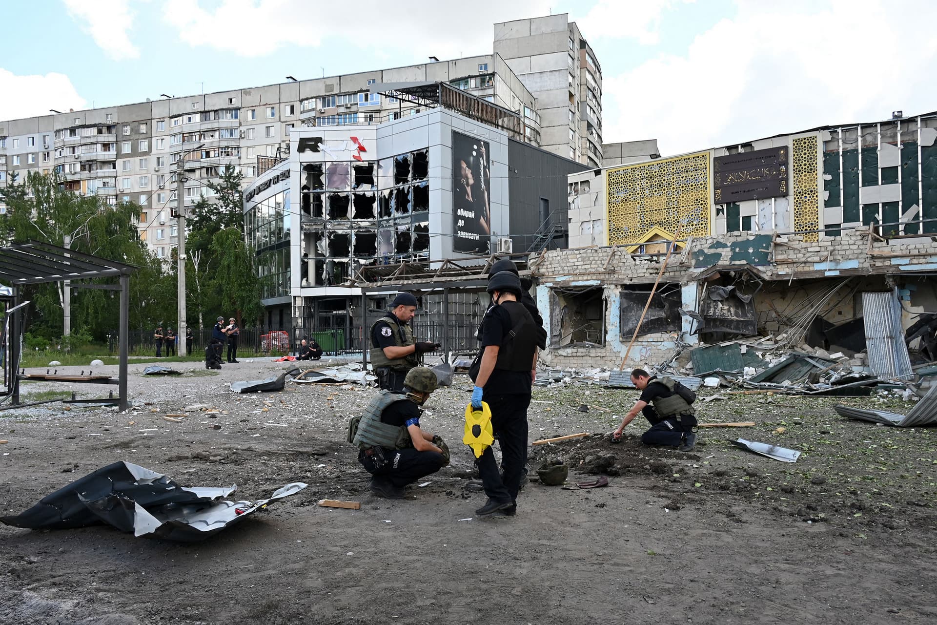 Police experts examine a crater left by a Russian missile strike at a bus stop in Saltivskyi, a northern district of of Kharkiv
