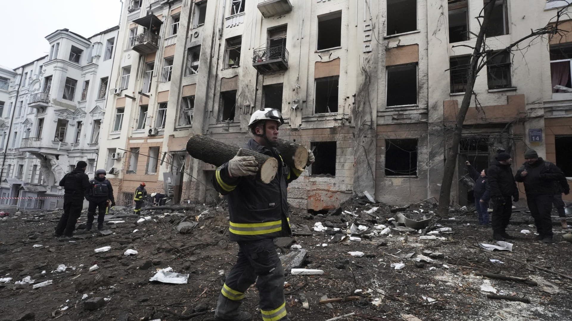 An emergency worker carries pieces of a sawn tree in front of a residential building which was hit by a Russian rocket at the city center of Kharkiv
