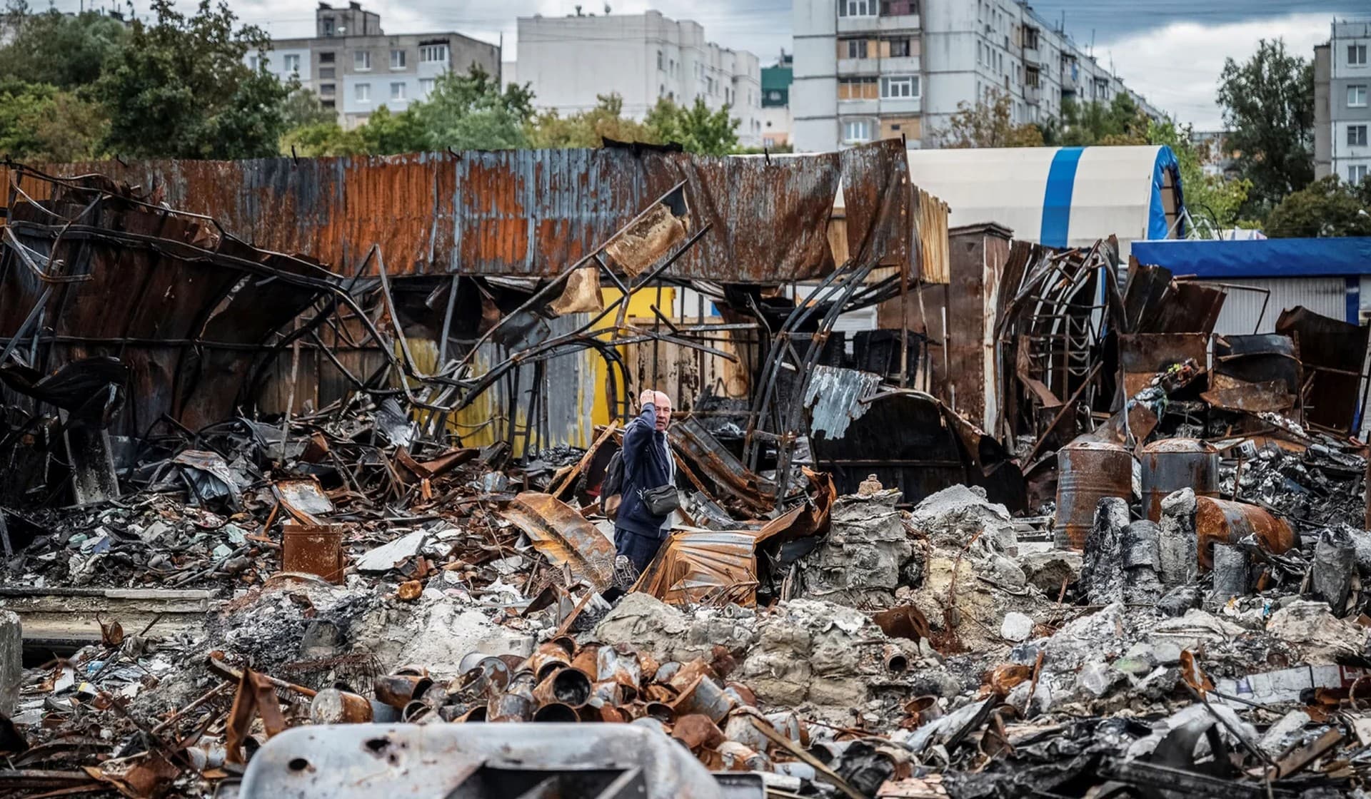 A local resident walks by a street market destroyed by military strikes in Saltivka