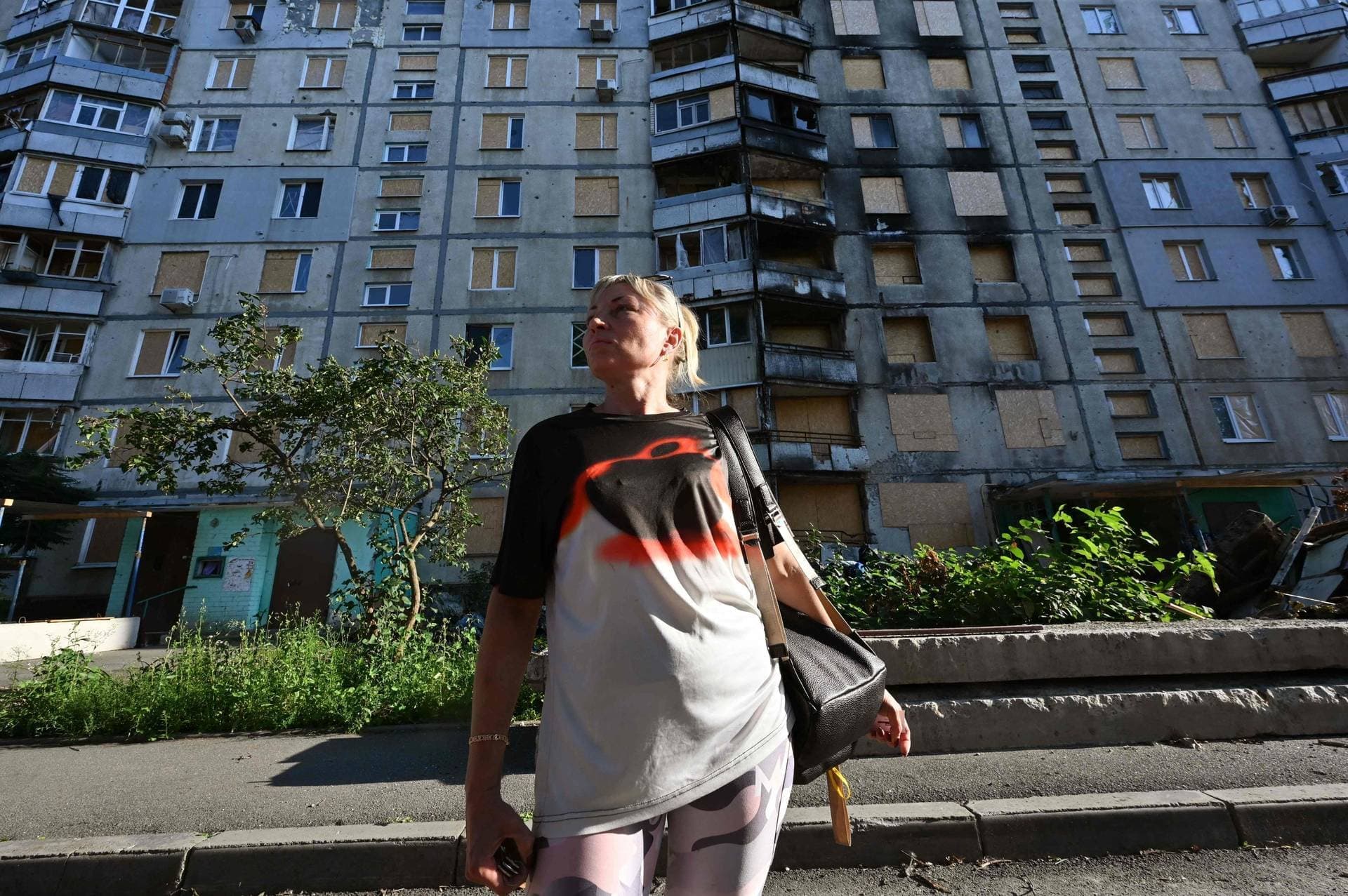 Tetiana Bezatosna stands in front of a heavily damaged by Russian strikes residential building in Kharkiv
