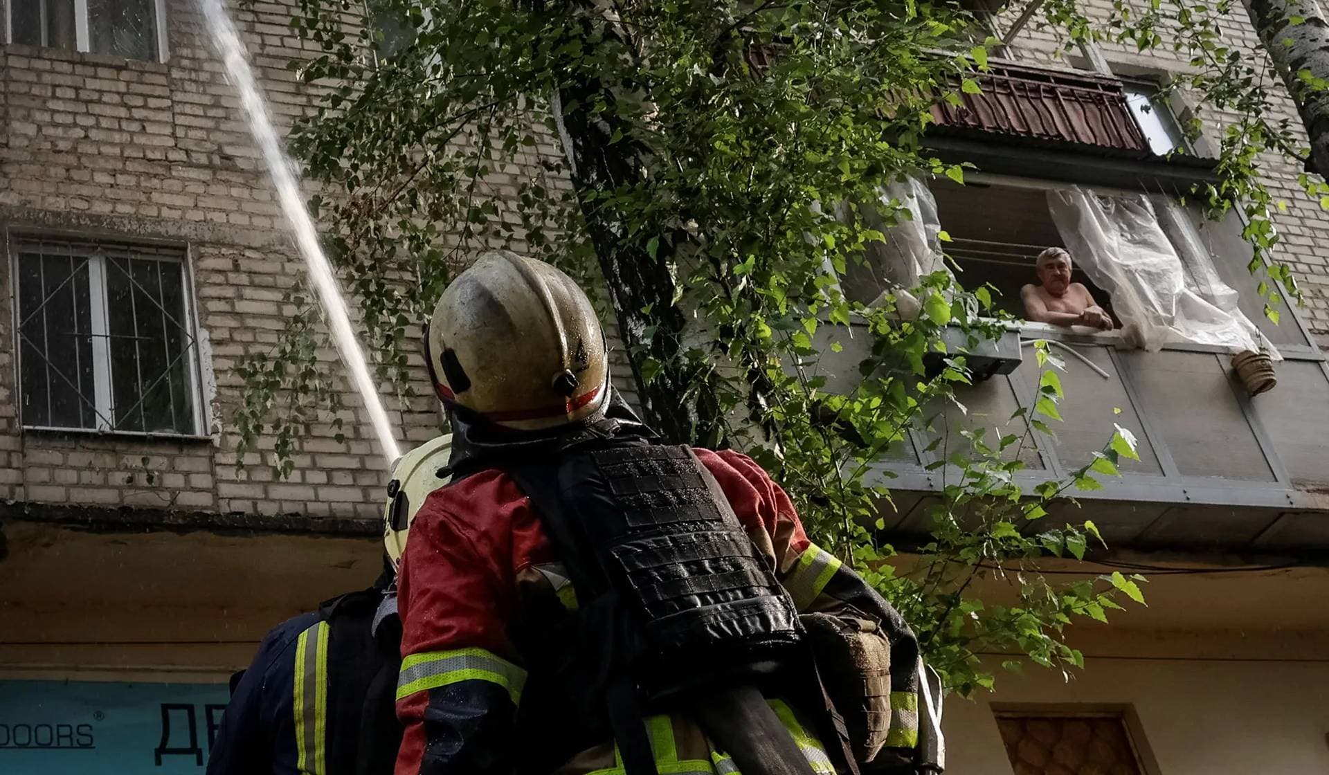 A resident looks as firefighters work at the site of an apartment building hit during a Russian drone strike in Kharkiv Region