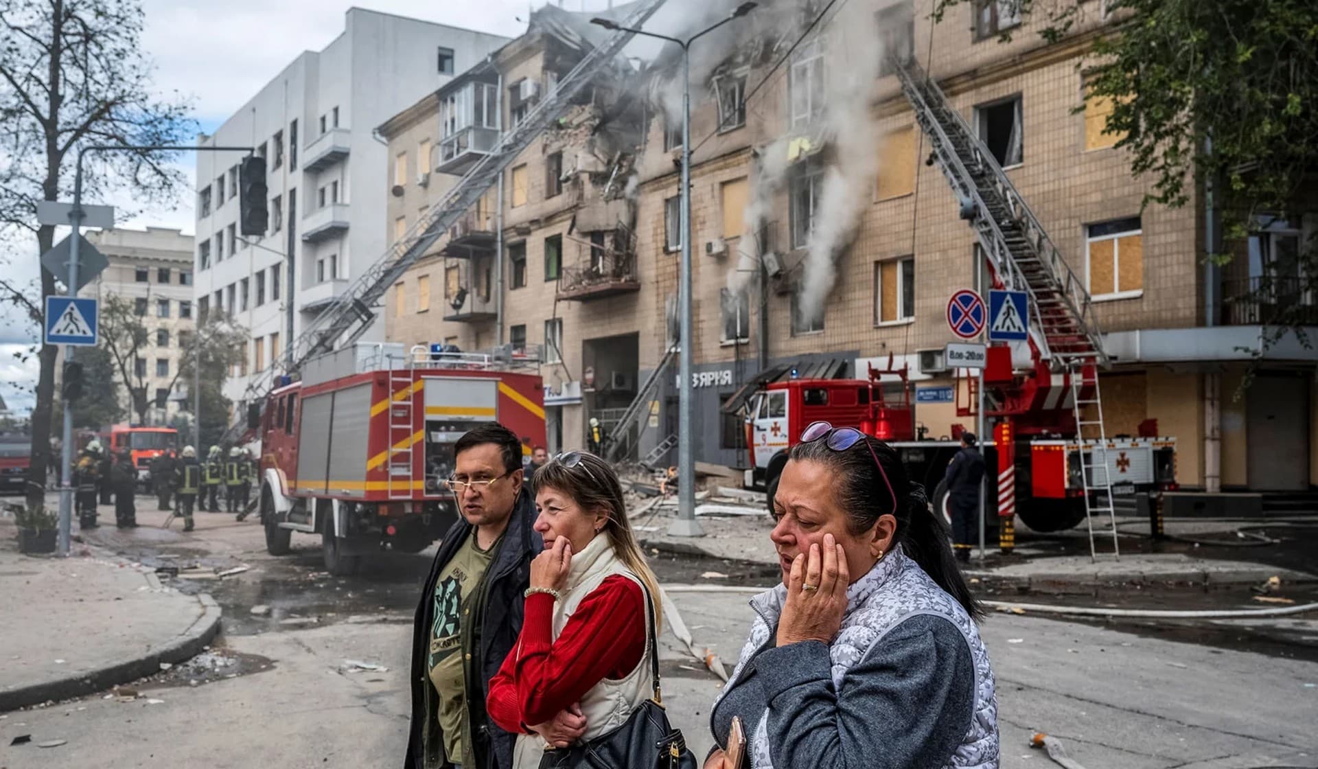 People stand outside of a residential building damaged by a Russian military strike in Kharkiv