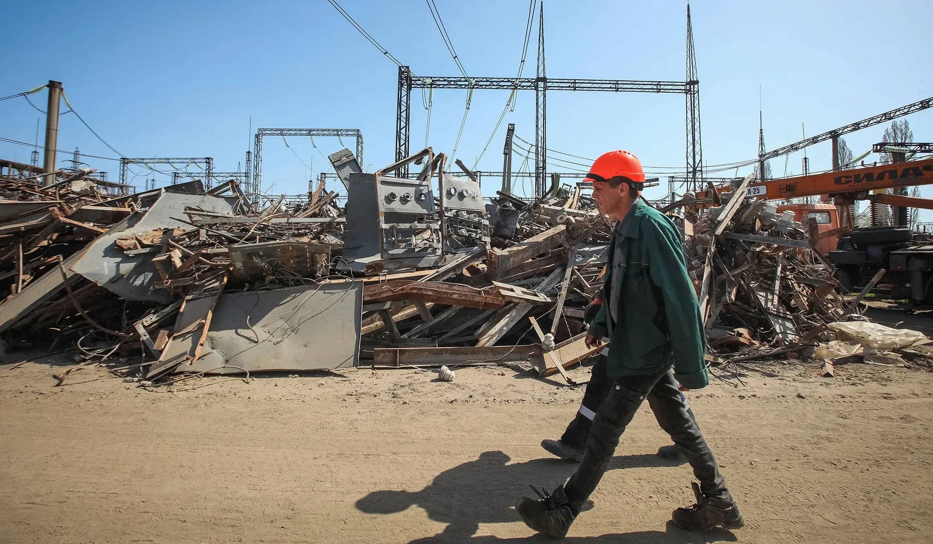 An employee of a critical power infrastructure installation walks by its destroyed part in Kharkiv