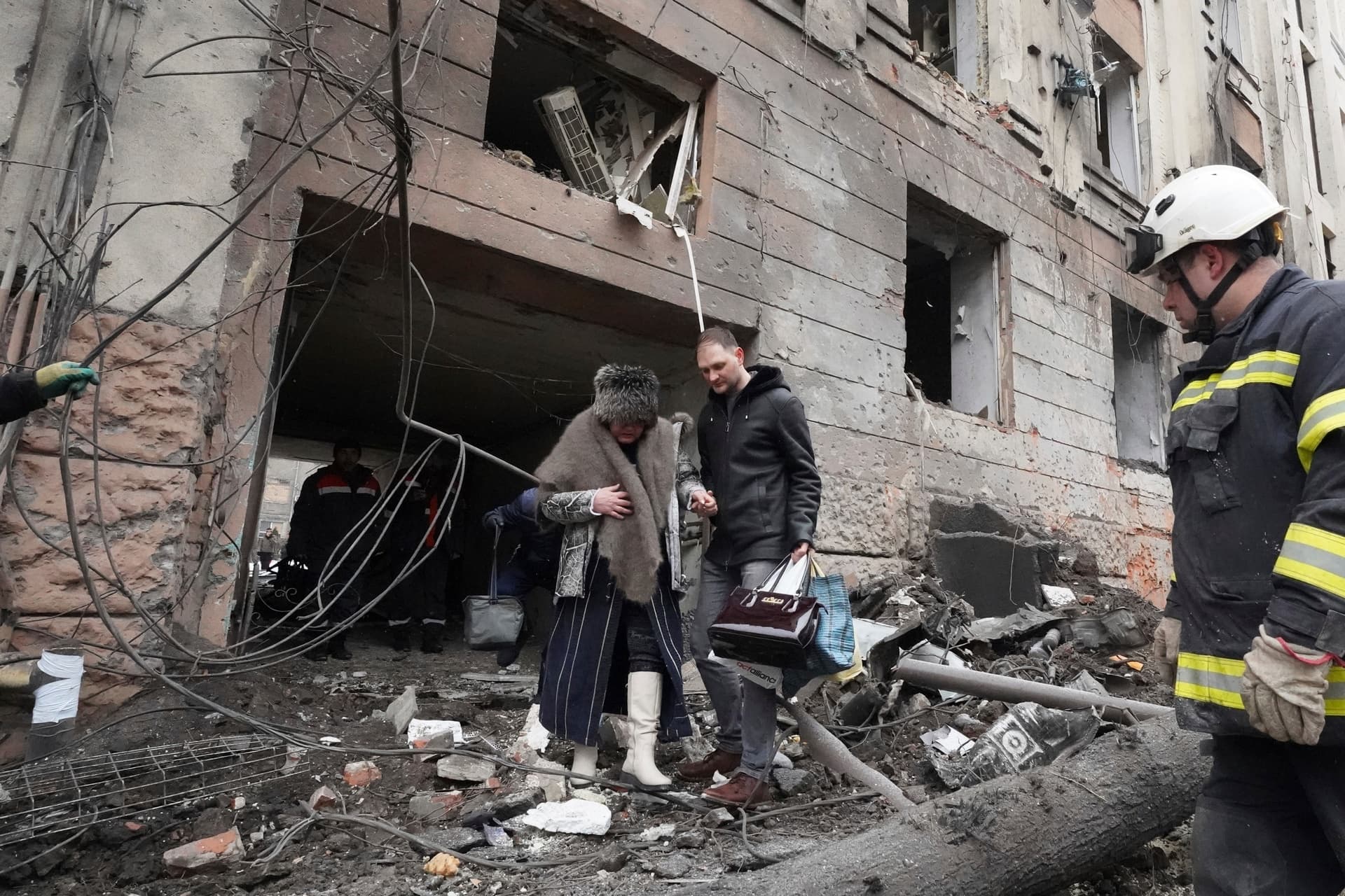 A man helps a woman to walk out from a residential building which was hit by a Russian rocket, in the city center of Kharkiv