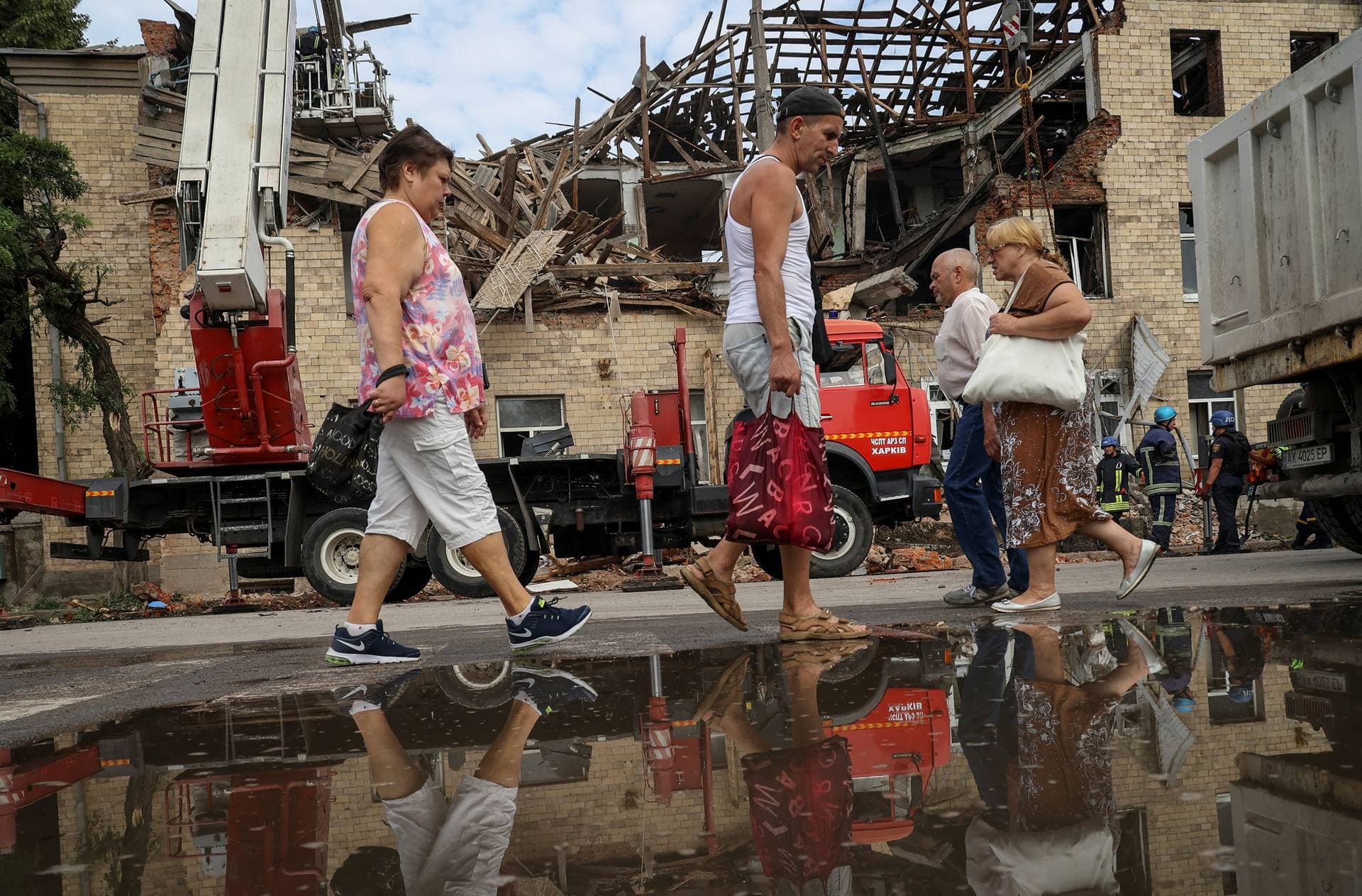 Local residents walk near a building damaged by a Russian drone strike in Kharkiv