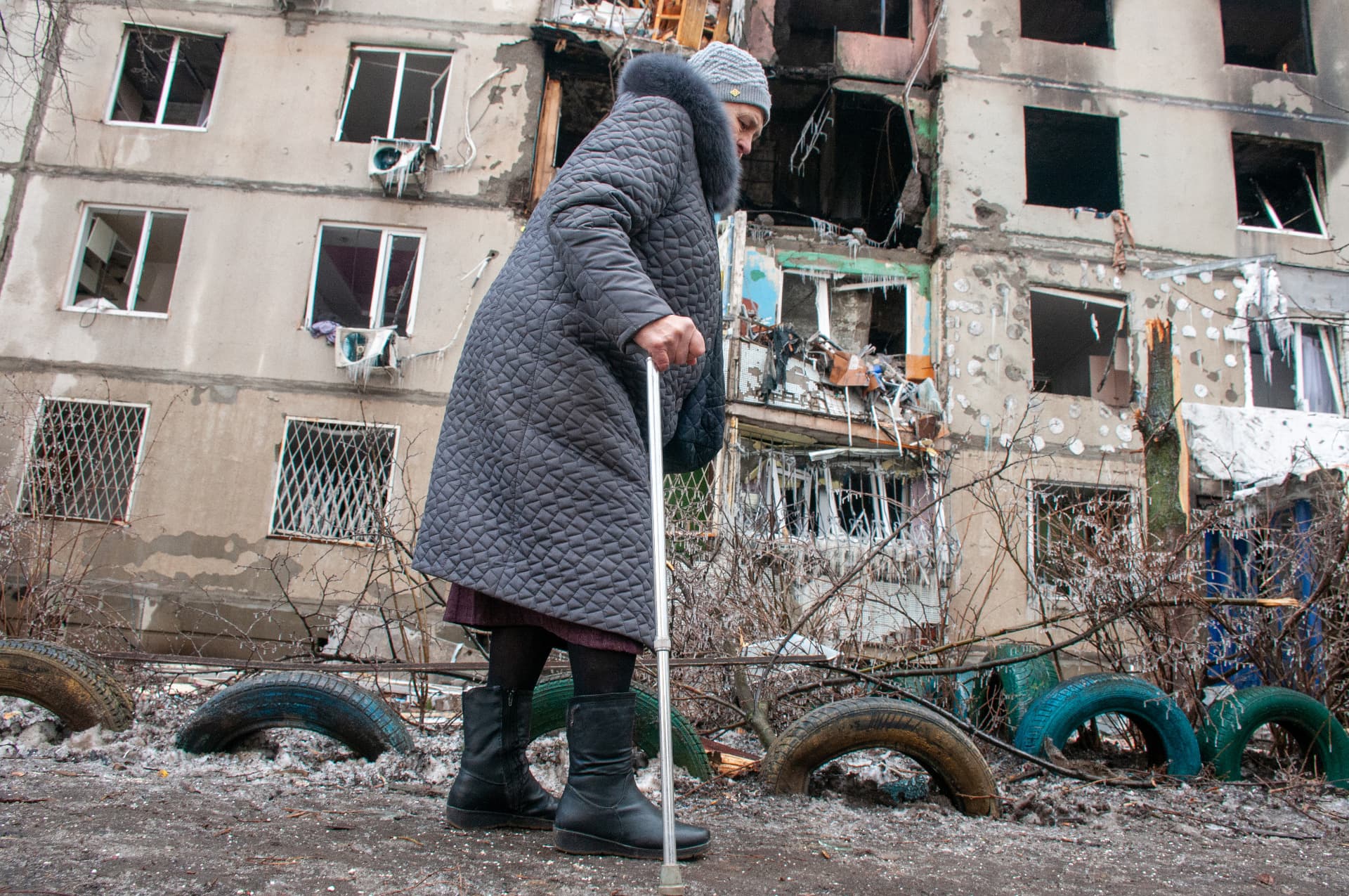 Senior woman walks near a residential building destroyed after shelling by the Russian military-occupiers in a residential area of Kharkiv