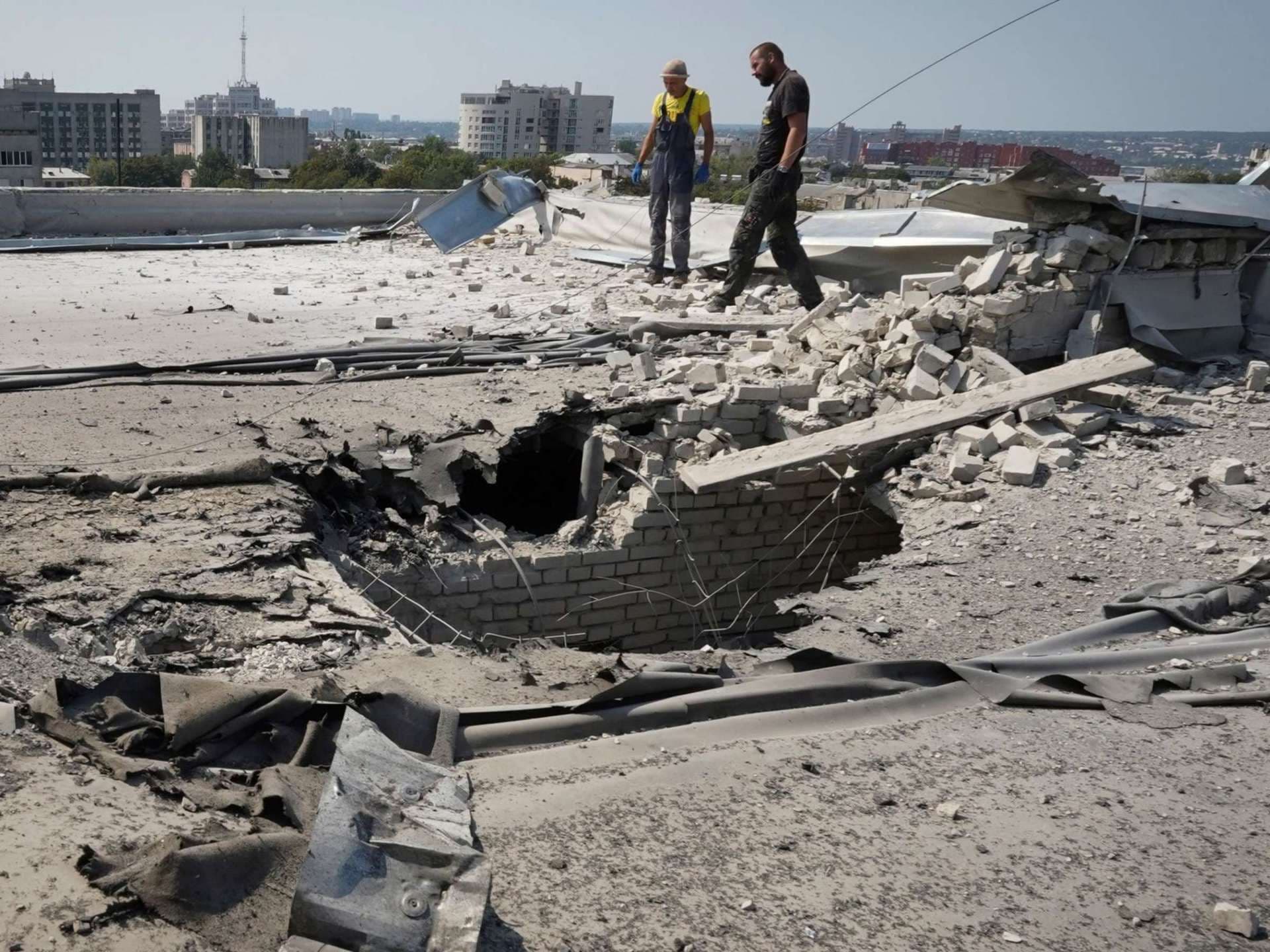 Communal employees work on a roof after it was damaged during a Russian attack in Kharkiv