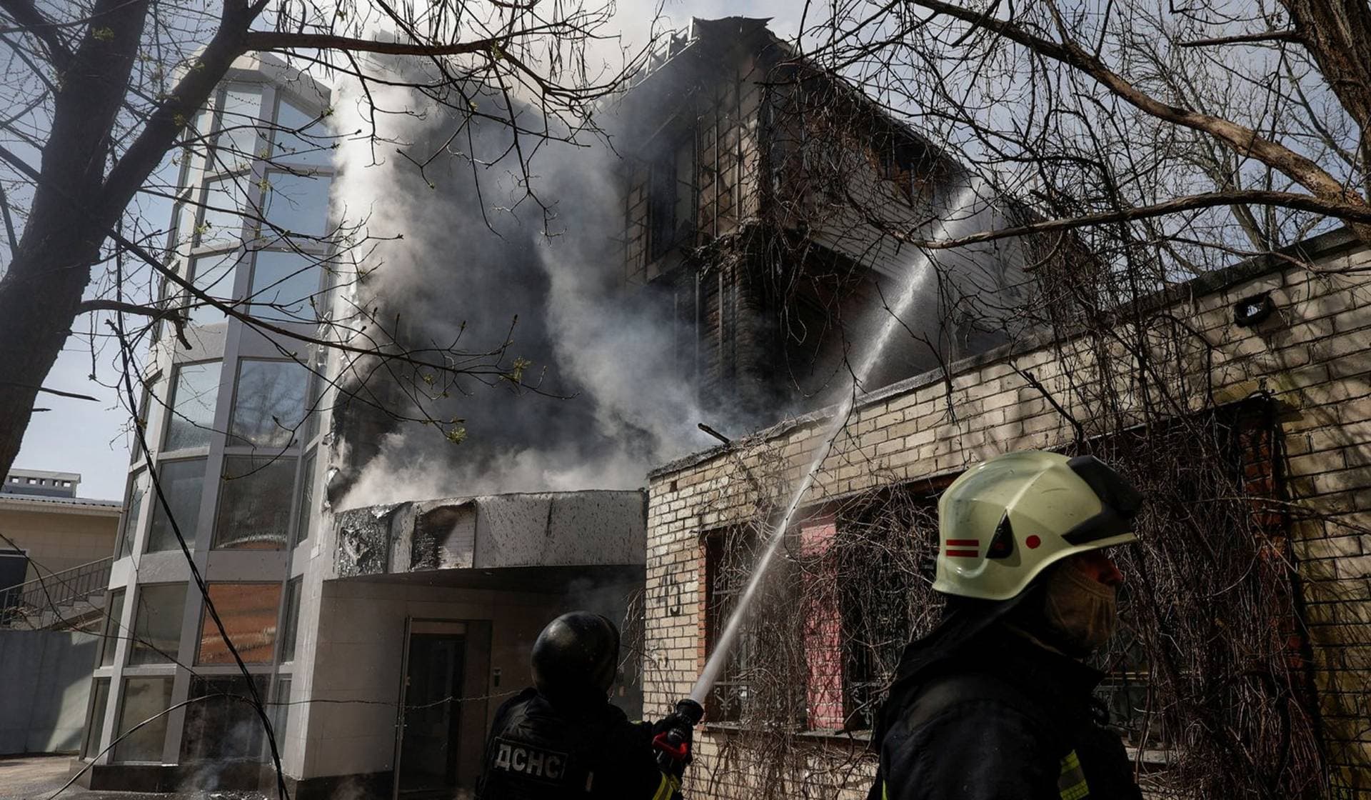 Firefighters work at the site where an office building was hit by a Russian drone strike in Kharkiv
