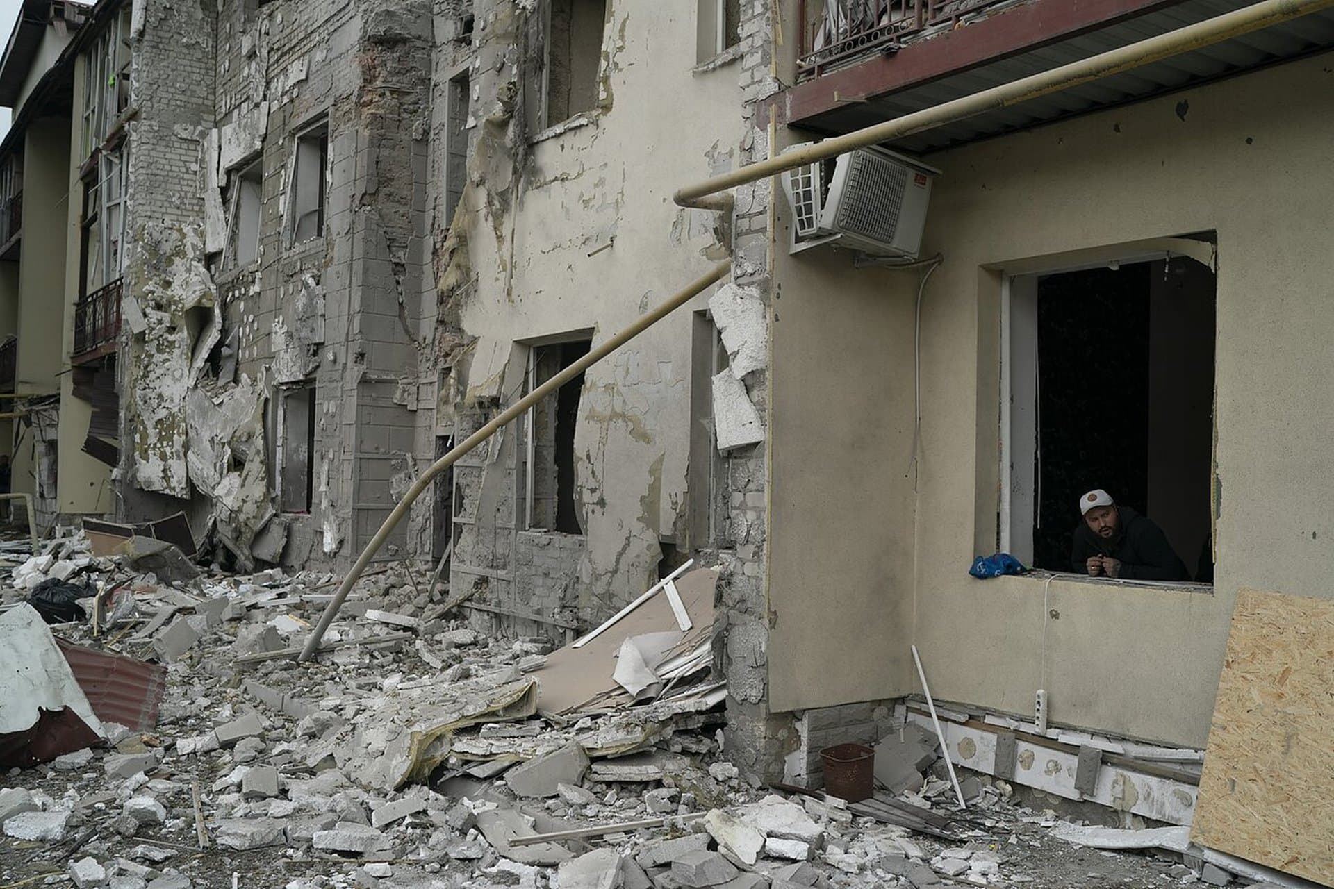 A man looks out from a window of a residential building that was damaged after a Russian attack in Kharkiv