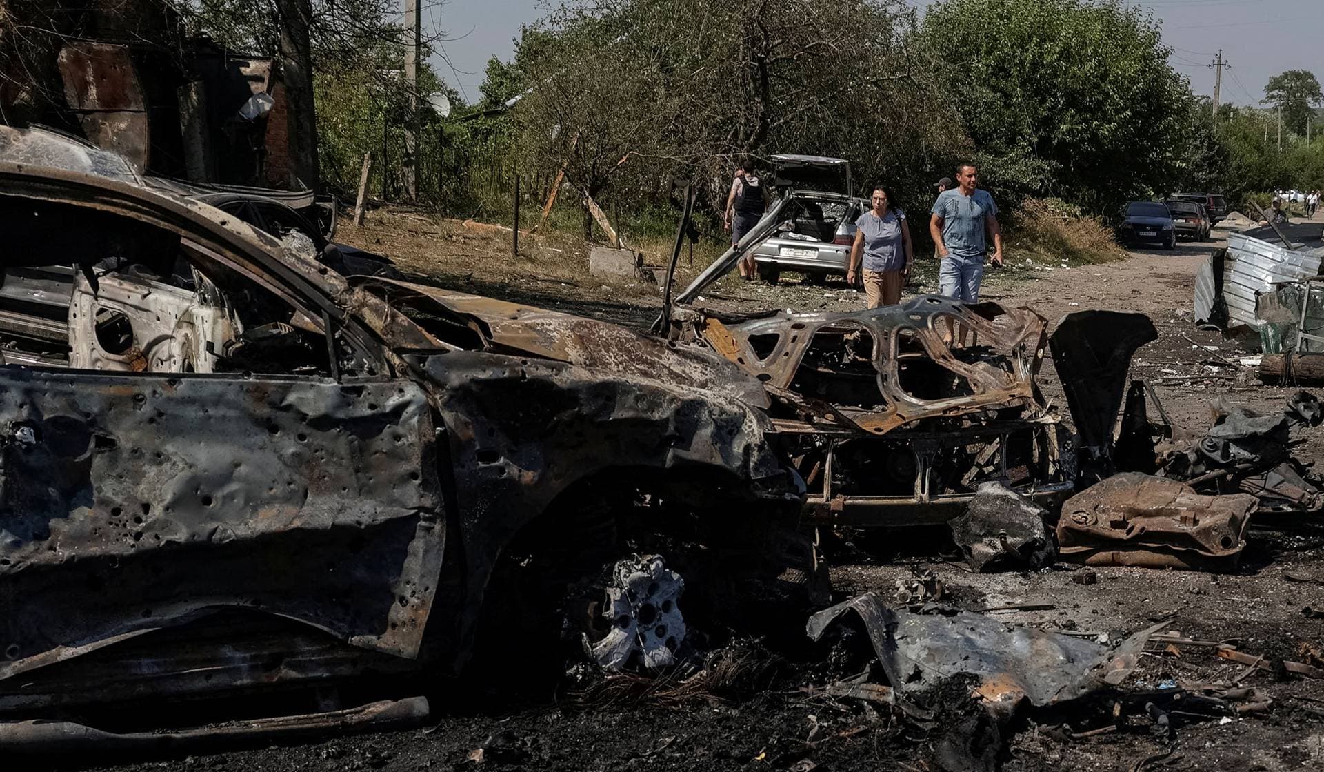 Residents walk at the site of Russian drone strikes in Pechenihy