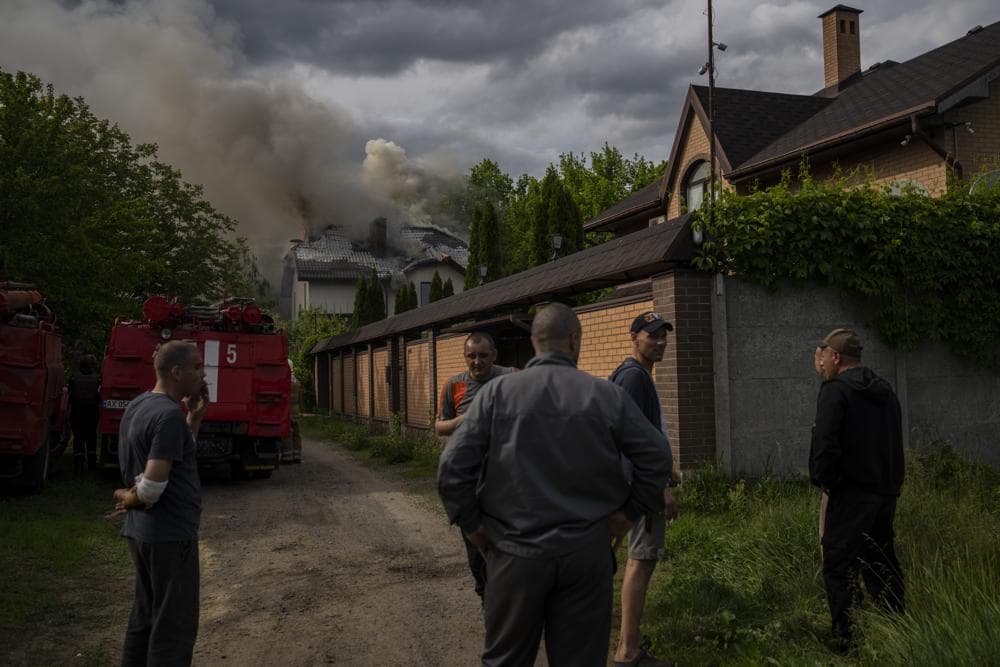 Neighbours gather around a house on fire that was hit during a Russian attack with a cluster-type munition in Kharkiv